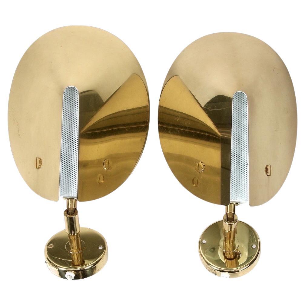 Coppia di appliques in ottone Aneta, Svezia 1980, presa singola a candelabro con paralumi in ottone stampato a forma di mezzo cono spesso con paralume centrale bianco traforato
Struttura in ottone e terminali in ottone.
I paralumi possono essere