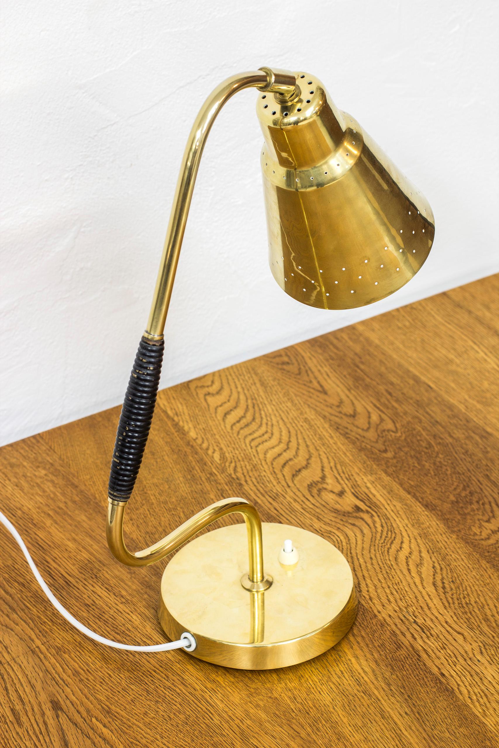 Table lamp produced by Swedish company Bergboms during the 1950s. Attributed to Eje Ahlgren. Made from solid polished brass and lacquered vine/rattan handle. Perforated, adjustable lamp shade. Light switch in working order. Very good vintage