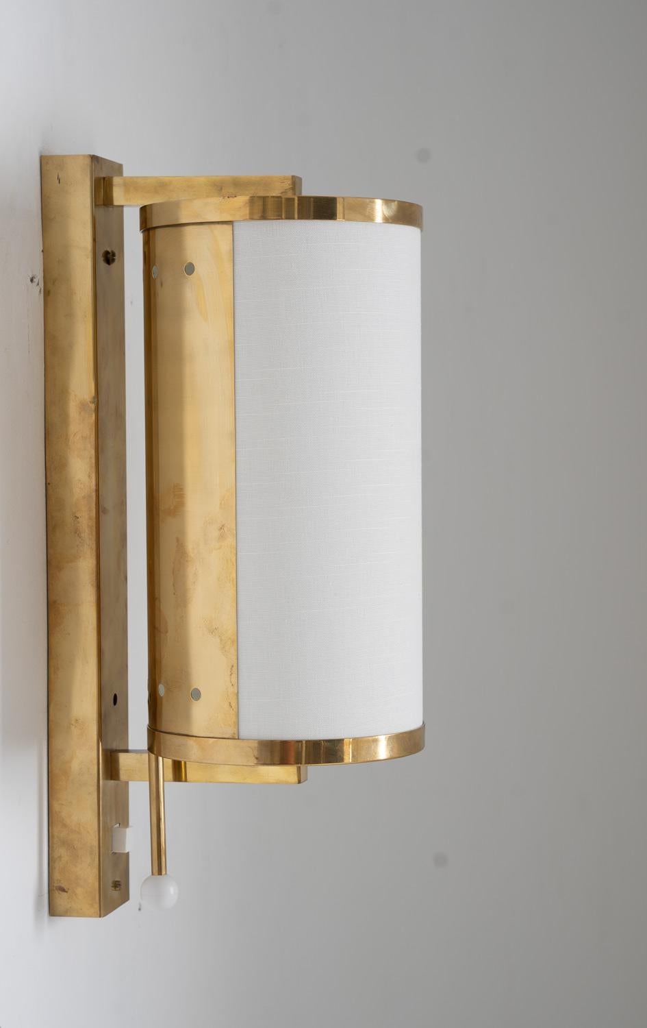 These charming Boréns wall lamps were produced in Sweden during the 1960s. 
They consist of a fabric-covered acrylic shade, fitted in a brass cylinder. The cylinder can be turned around, to direct the light in any angle. 

Very good restored