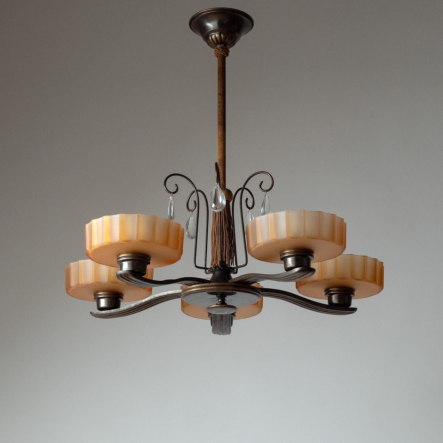 Lampadario svedese Grace in bronzo e vetro avana degli anni '30, attribuito a Böhlmarks. Struttura patinata scura con cinque diffusori in vetro avana patinato. Il gambo è rivestito in tessuto con nappe originali e decorazioni in bronzo con cristalli