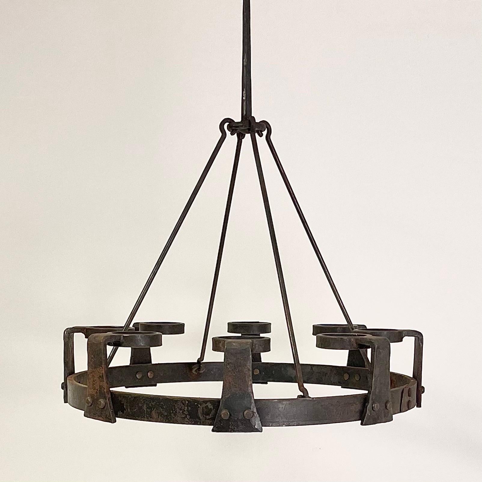 This is the Swedish brutalist 1970s sports cabin chandelier in wrought iron by the Swedish artist Erik Höglund and the blacksmith Lars Larsson.
It comes in a circular, very rough shape. Eight bended candleholder arms are mounted with large rivets in