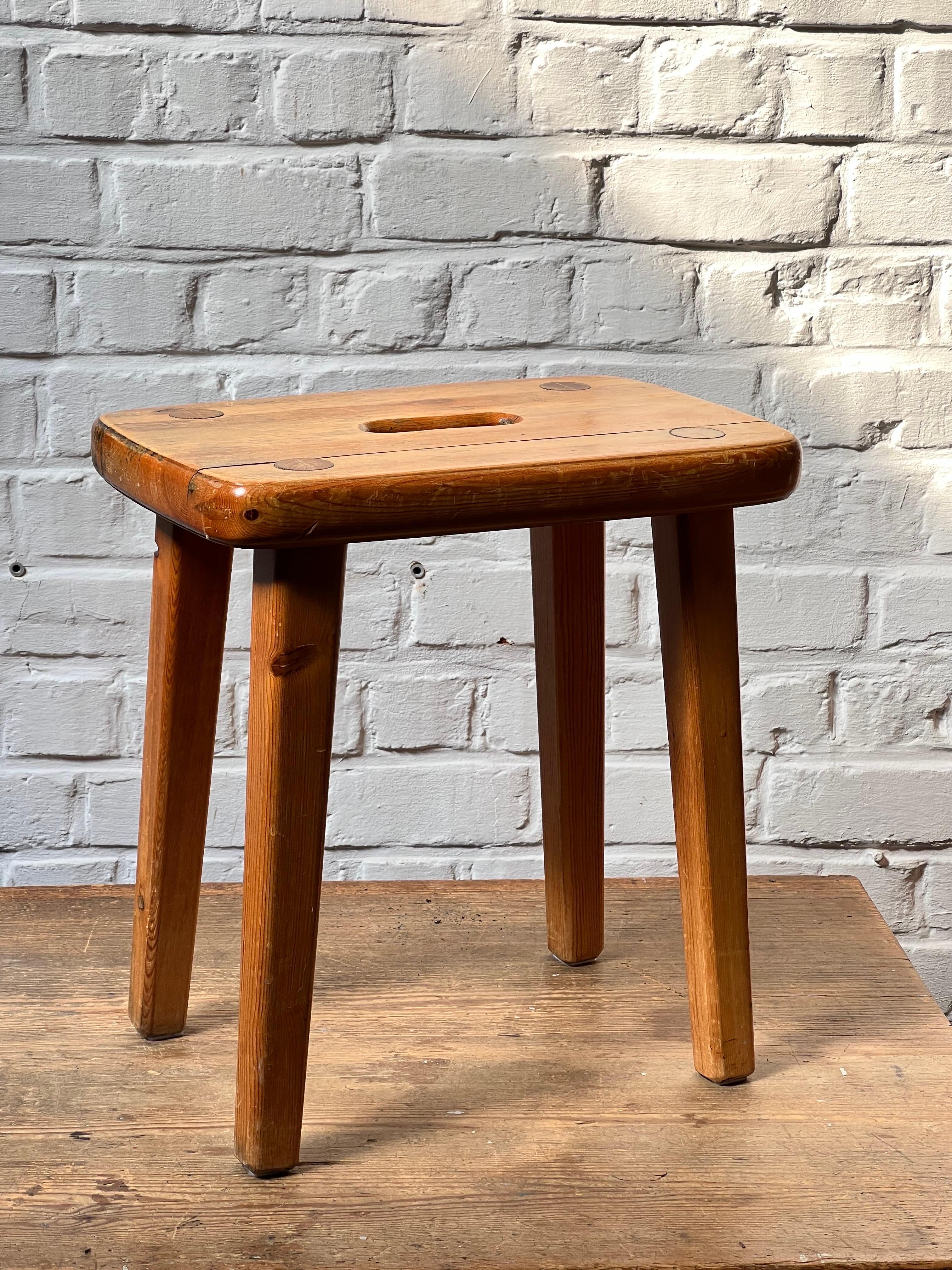 Handmade Swedish stool with massive slasy of pine. It is a rectangular shaped. The joinery is really elegant. The top is patinated and shows various shades of  honey tones. Elegant and brutalist describe that stool properly. Very strong stool.