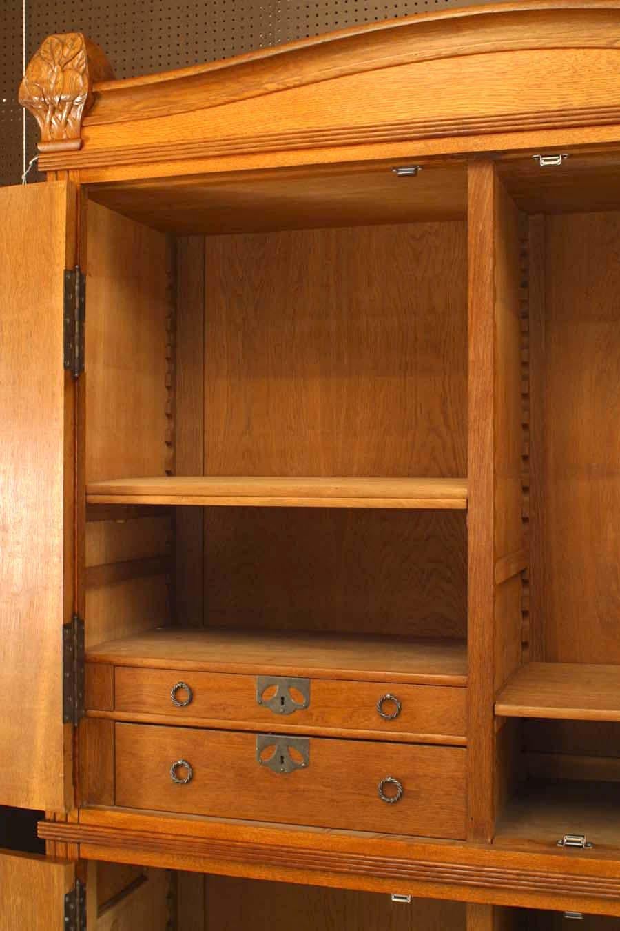 Swedish Arts & Crafts (circa 1915) oak 4 door cabinet with carved floral design finials & trim and decorative metal hardware (by designer and architect Carl Westman).
 