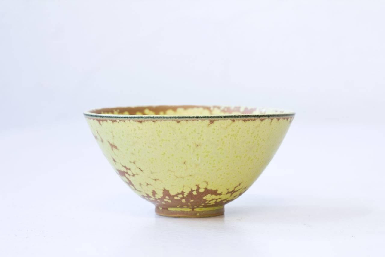 Stoneware bowl designed by Gunnar Nylund. Handmade at Rörstrand in Sweden during the 1950s. Brown and yellow glaze with freckled lime color.
Hand signed with initials of ceramist. 1st quality mark.

