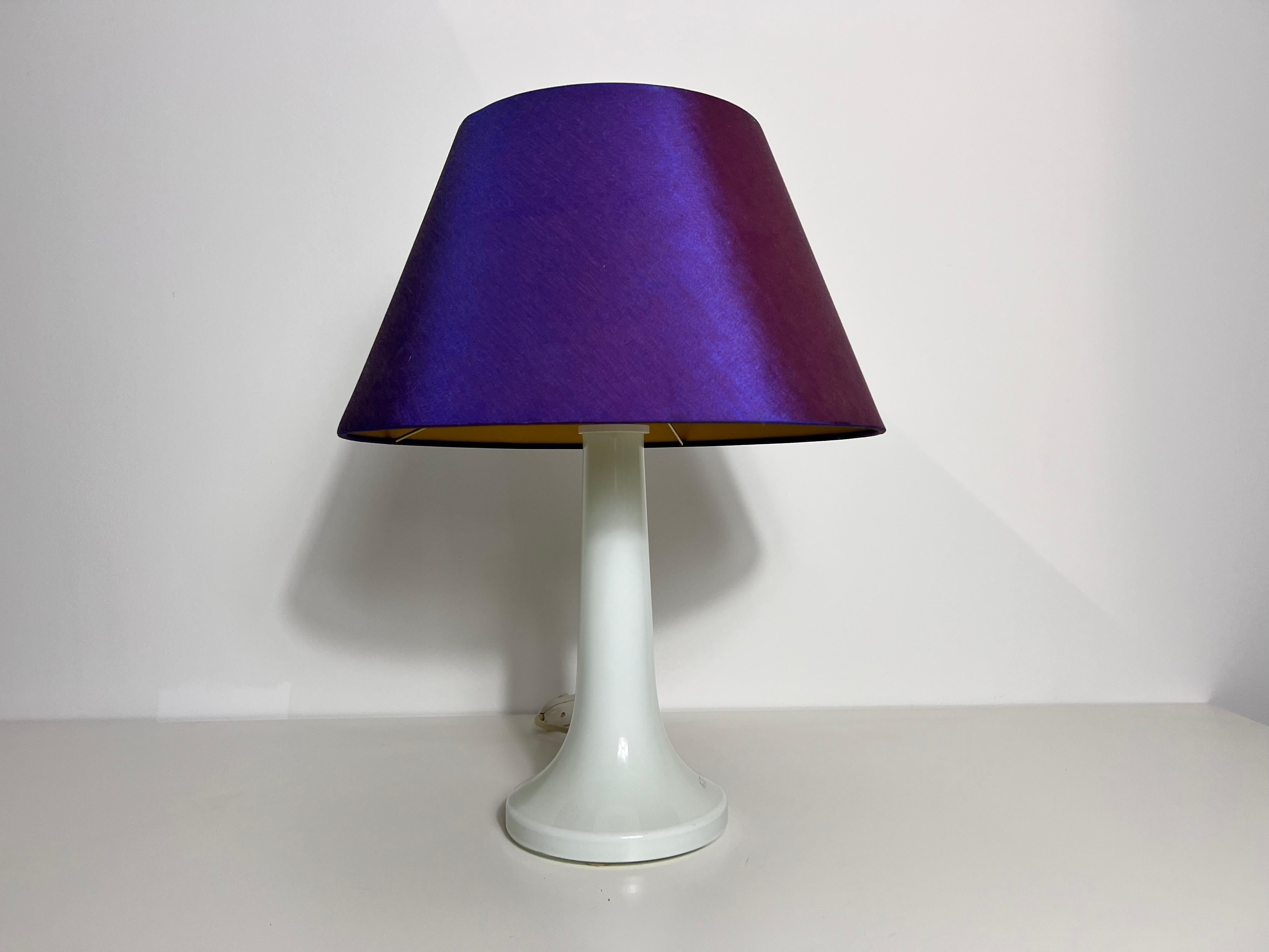 Diese atemberaubende Tischleuchte aus dem Schweden der 1970er Jahre fängt die Eleganz des Designs aus der Mitte des Jahrhunderts mit einem Hauch von Space Age-Flair ein. Der Sockel aus glänzender weißer Keramik strahlt mit seiner schlanken, sich