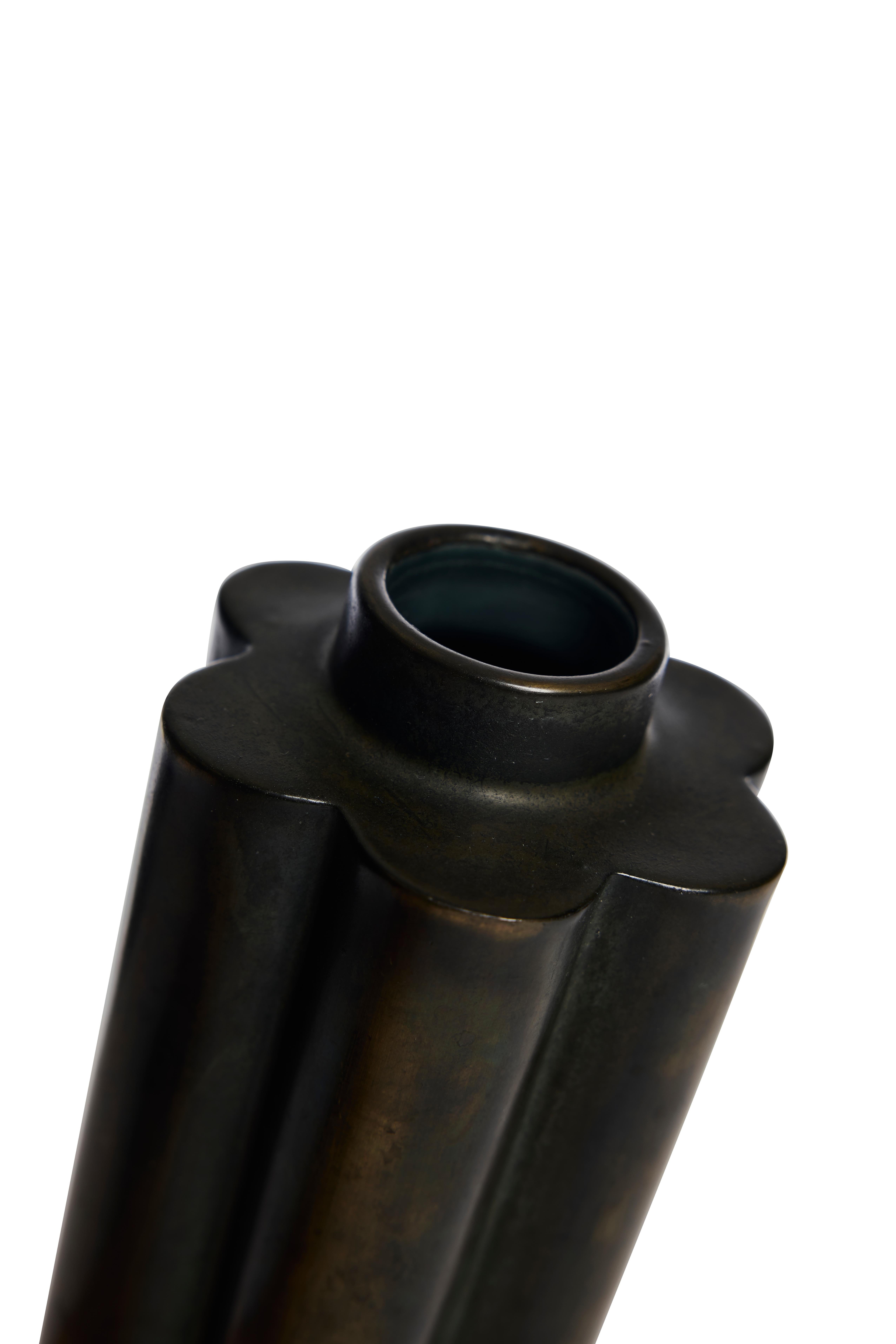 Un sorprendente vaso in ceramica dalla silhouette scultorea e scanalata, firmato GePe e risalente agli anni Trenta. Rifinita con uno smalto bronzo dalle sfumature intense, la superficie brilla di sfumature verdi, marroni e metalliche, dando