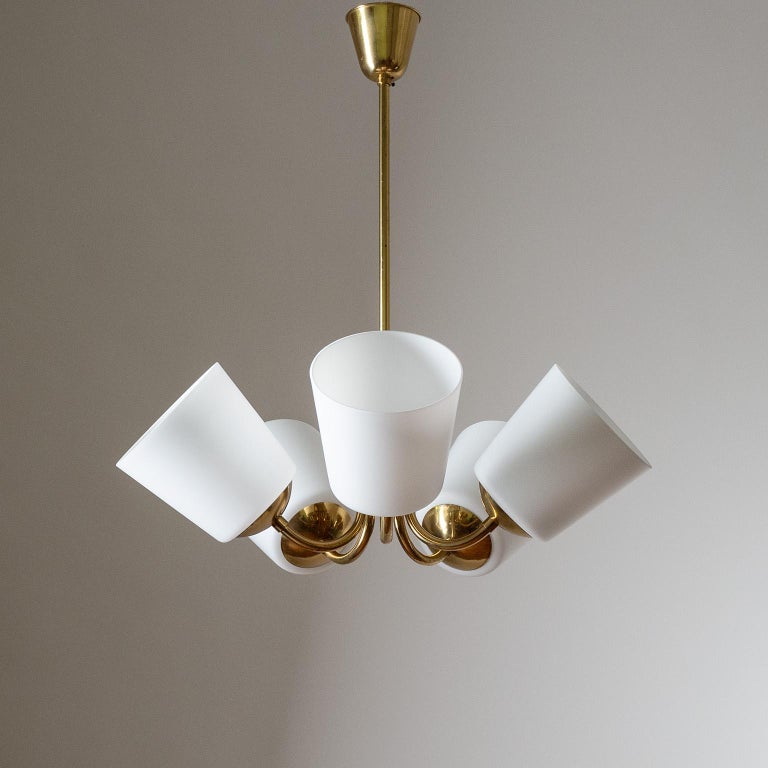 Five-arm Swedish brass chandelier from the 1950s. Unusual minimalist and compact design with large satin glass diffusers pointing upward. Five original brass E27 sockets with new wiring.
Measures: Height 73cm (28″), Diameter 64cm (25″), Glass 16cm