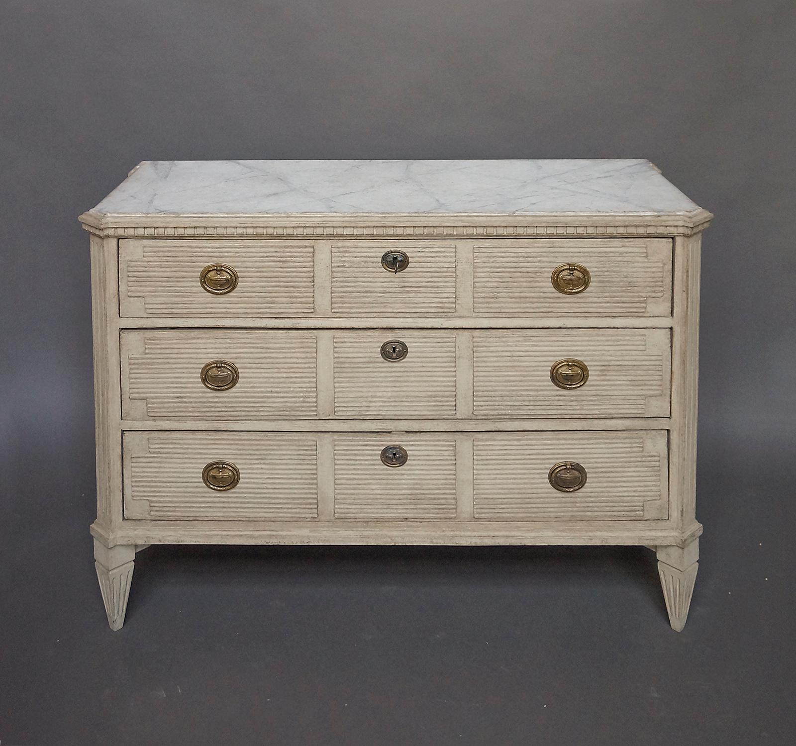 Swedish chest of drawers, circa 1860, with three reeded drawers and brass hardware. Shaped top with marbleized finish and dentil molding. Canted corner posts and tapering square feet.