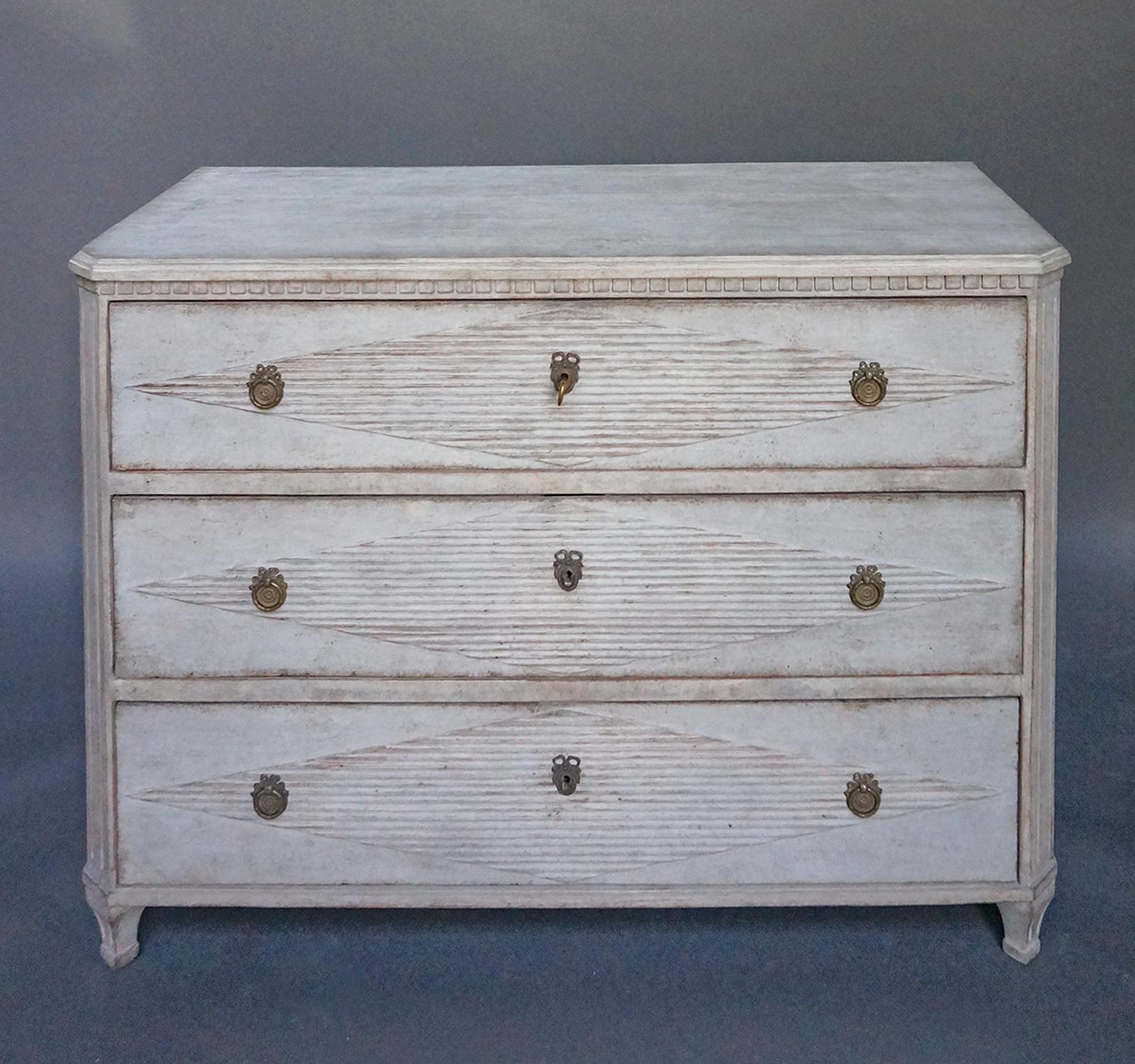 Chest of drawers in the Gustavian style, Sweden, circa 1850, with raised lozenges on the drawer fronts. Shaped top with dentil molding, canted corners and tapering square legs. Brass pulls and escutcheons.