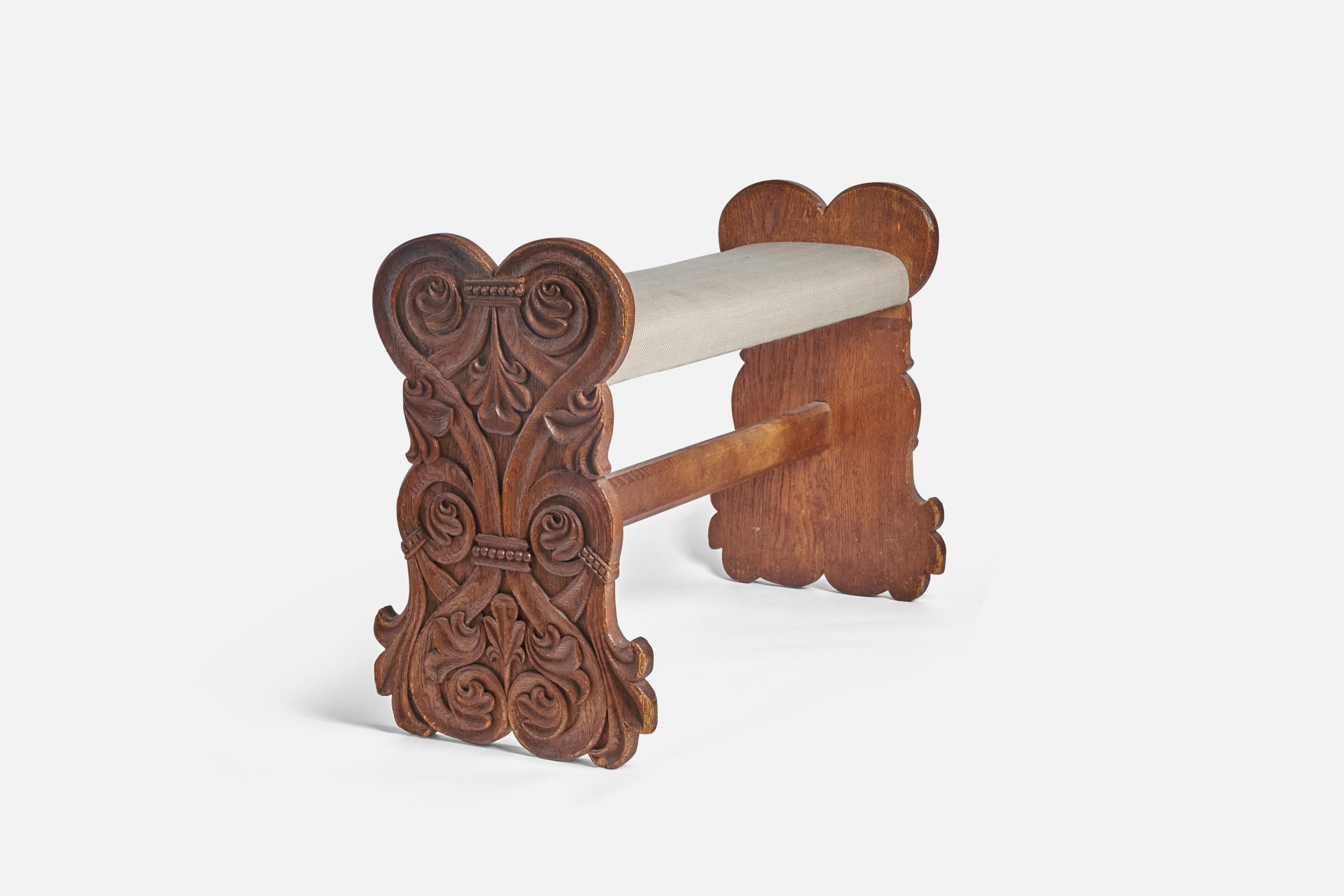 A carved and stained oak and beige fabric bench designed and produced in Sweden, circa 1910s. 