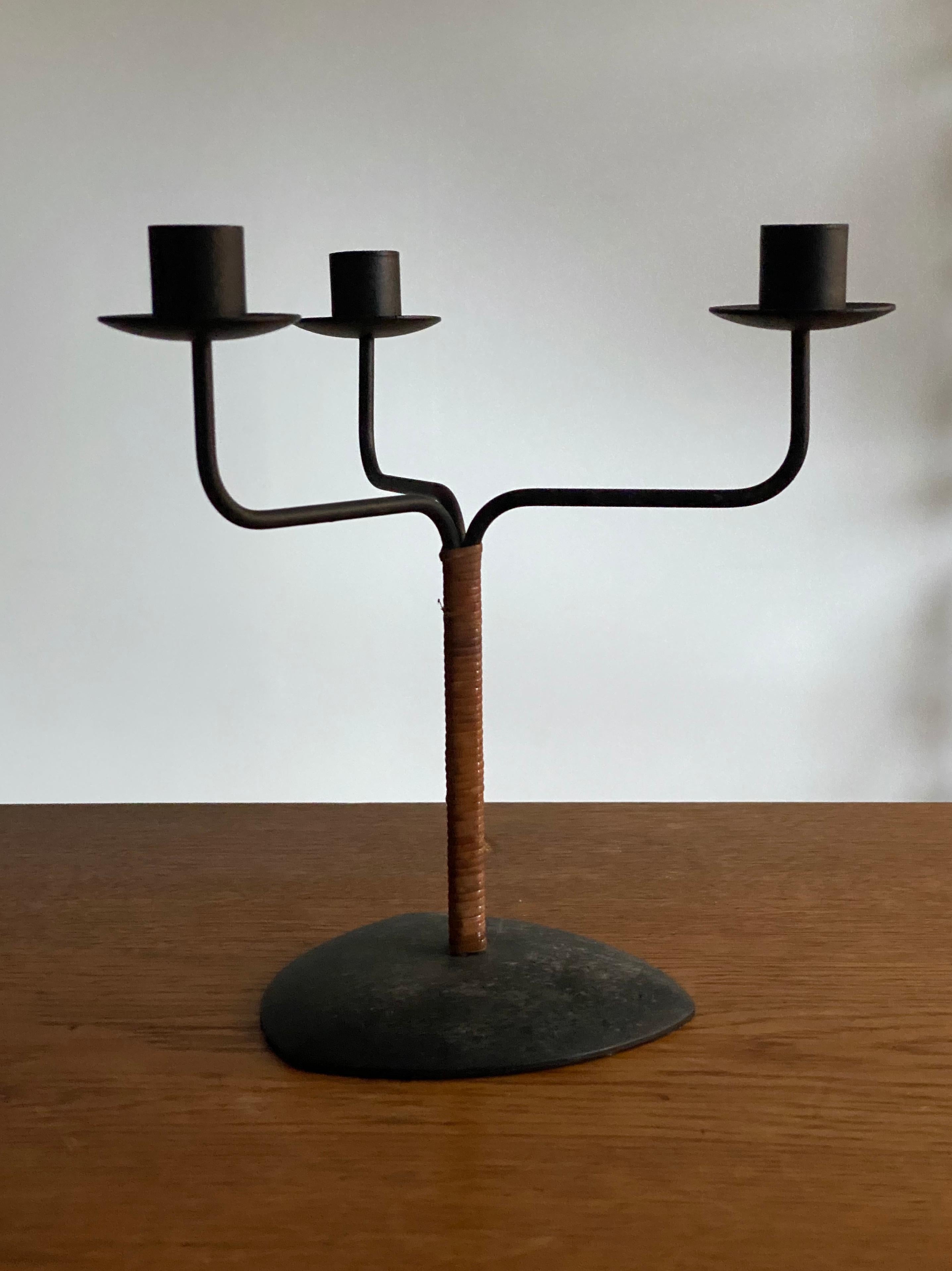 A small modernist candelabra or candle tree, circa 1970s. In black painted metal. Fits 3 normal sized Scandinavian candles. With original cane-wrapped rod.