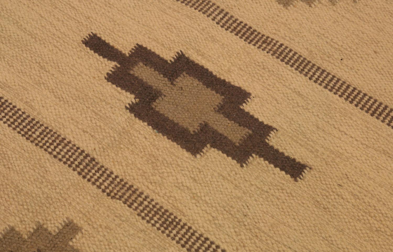 This is a semi-antique Swedish kilim woven circa 1920-1950 and it measures 235 X 172 CM. It features a simplistic pattern with geometric cross motifs that fit perfectly in any modern setting. Moreover it uses an incredible range of browns, sepia and