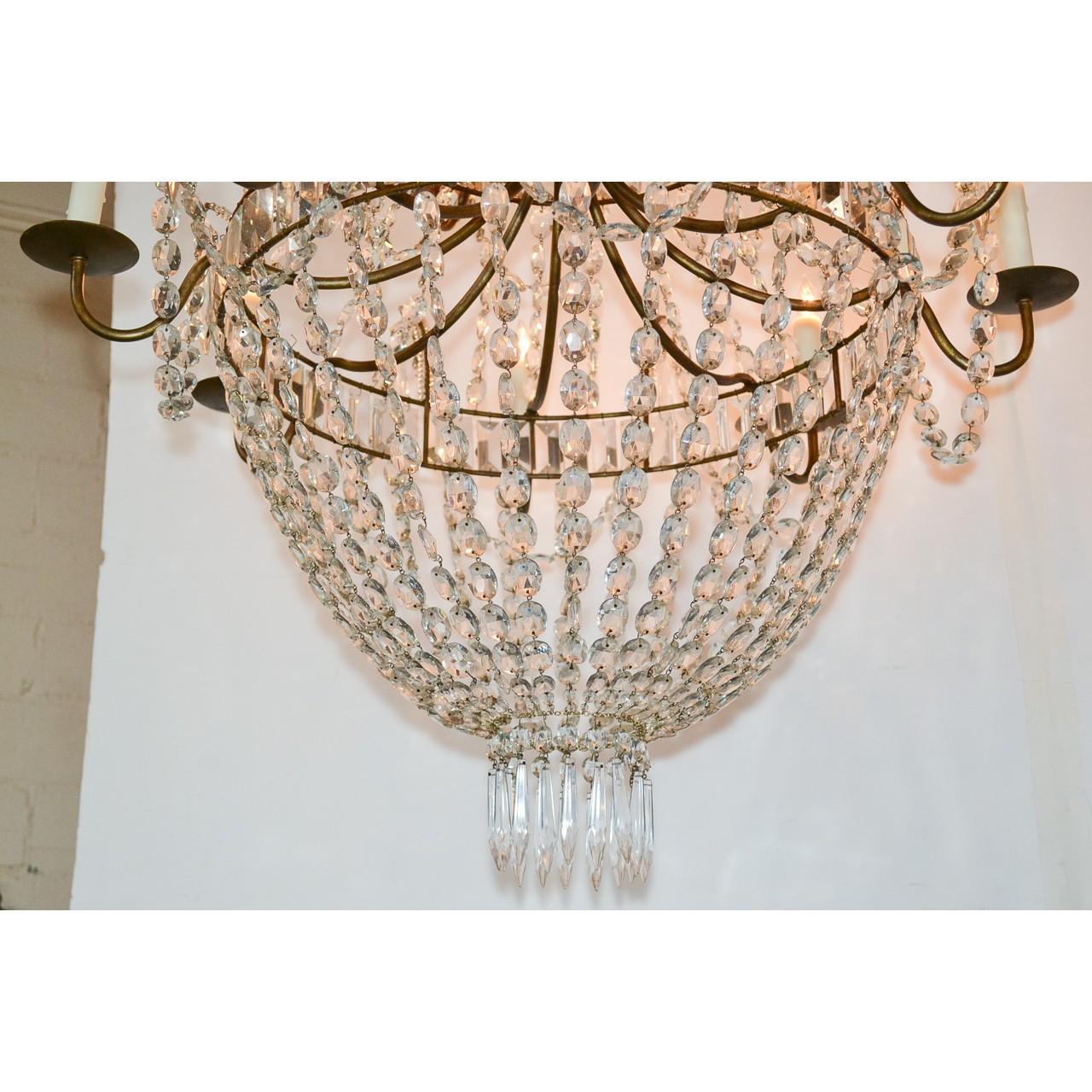Gorgeous Swedish hand-cut crystal basket form chandelier having three graduated banded tiers inset with baguette crystal prisms. Each tier draped with strands of bead cut crystals and accented with diamond-shaped prisms, and icicle drops. Mounted