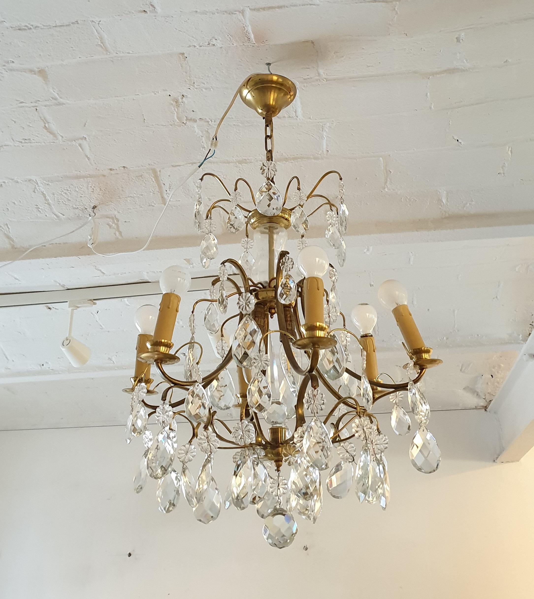 Beautiful chandelier with antique crystals with six bulbs. The ceiling lamp is finished with brass elements. This lamp is from Sweden Age, circa 1920.
   