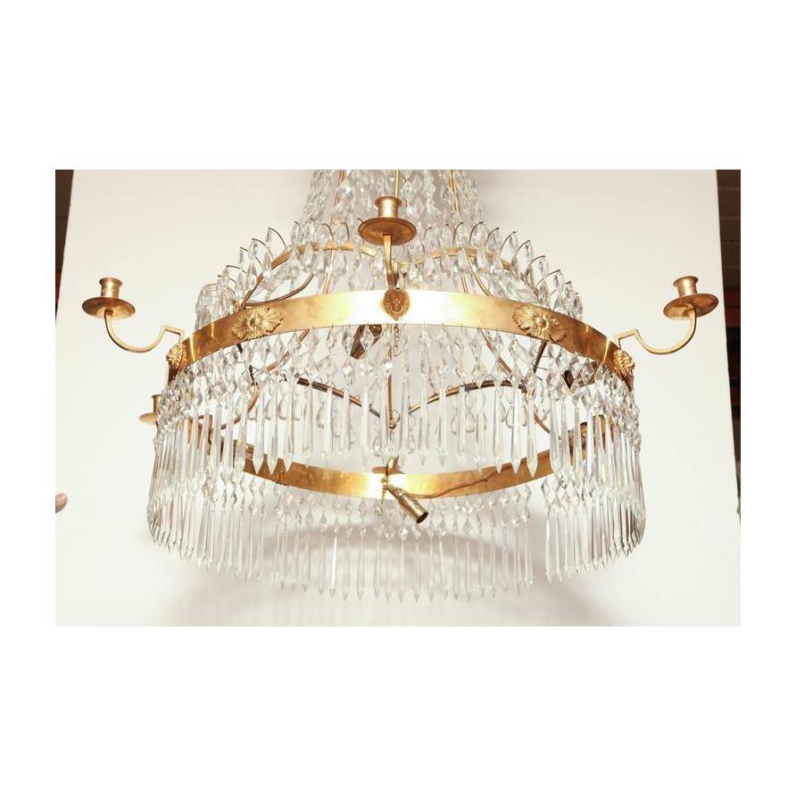 Large Swedish crystal and bronze six-light chandelier with arches between candles, elaborate corona and lion head motifs.

Early 19th century.

Measures: 46 H, 33.5 D.