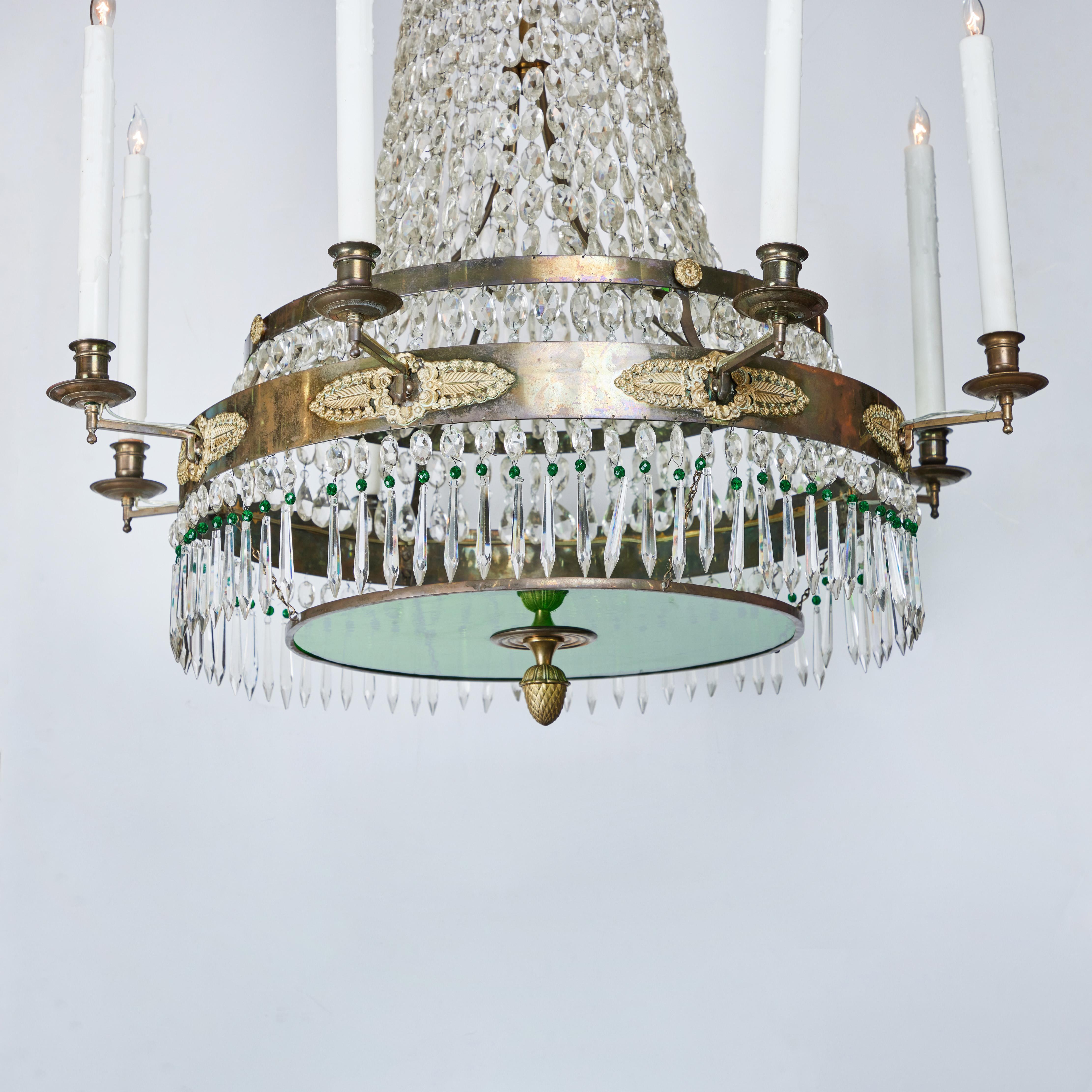 An elegant, bronze and crystal, eight-arm chandelier with 2 emerald green glass plates and green accent crystals. The top tier features a cascade of crystal hovering above long crystal swags, creating a luxurious, but graceful body that terminates