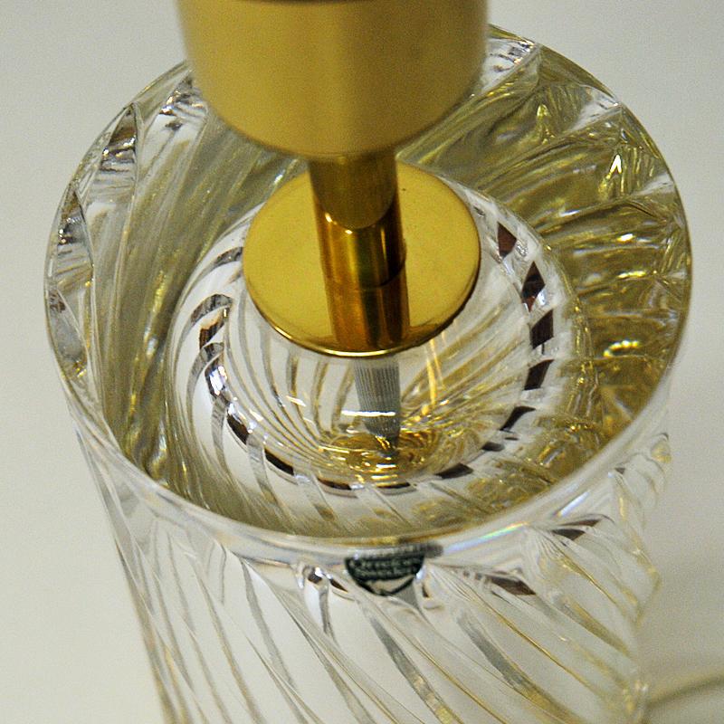 Lovely glass and brass table lamp model designed by Olle Alberius for the Swedish glasswork company Orrefors in the 1970s. This lamp is made of crystal glass with a twirly look on a brass foot base. The lamp is heavy with an elegante shape and