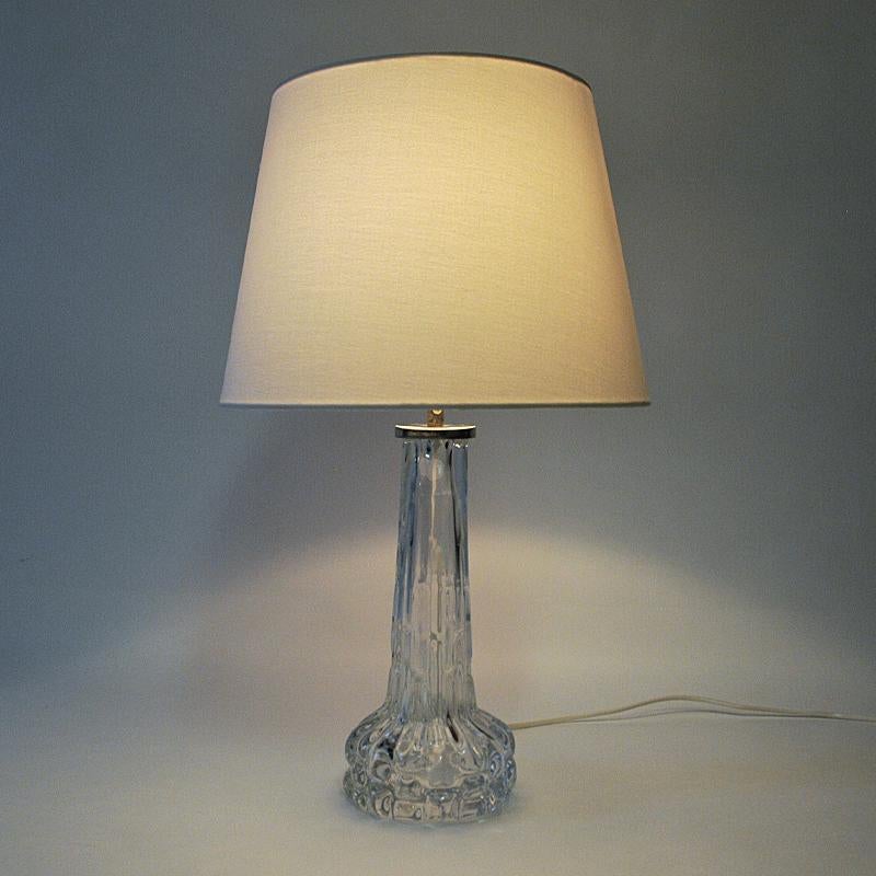 Lovely midcentury glass table lamp model RD designed by Carl Fagerlund for the Swedish glasswork company Orrefors in the 1950s. The lamp is made of crystal glass and reminds of frozen water- capped with a polished metalbase on top with the Orrefors