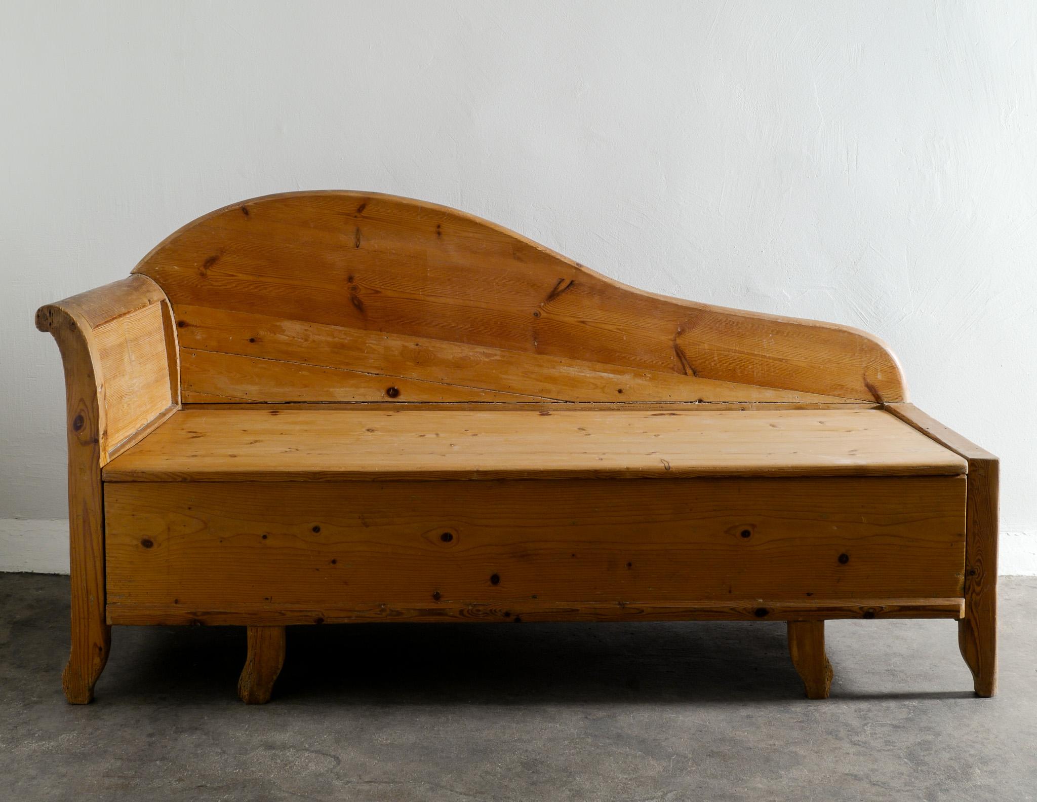 Rare and early antique Swedish pine bench canapé / sofa produced in Sweden early 1920s with a nice curved free form backrest. Original condition. Hidden storage underneath the seating. 

Dimensions: H: 90 cm / 35.50