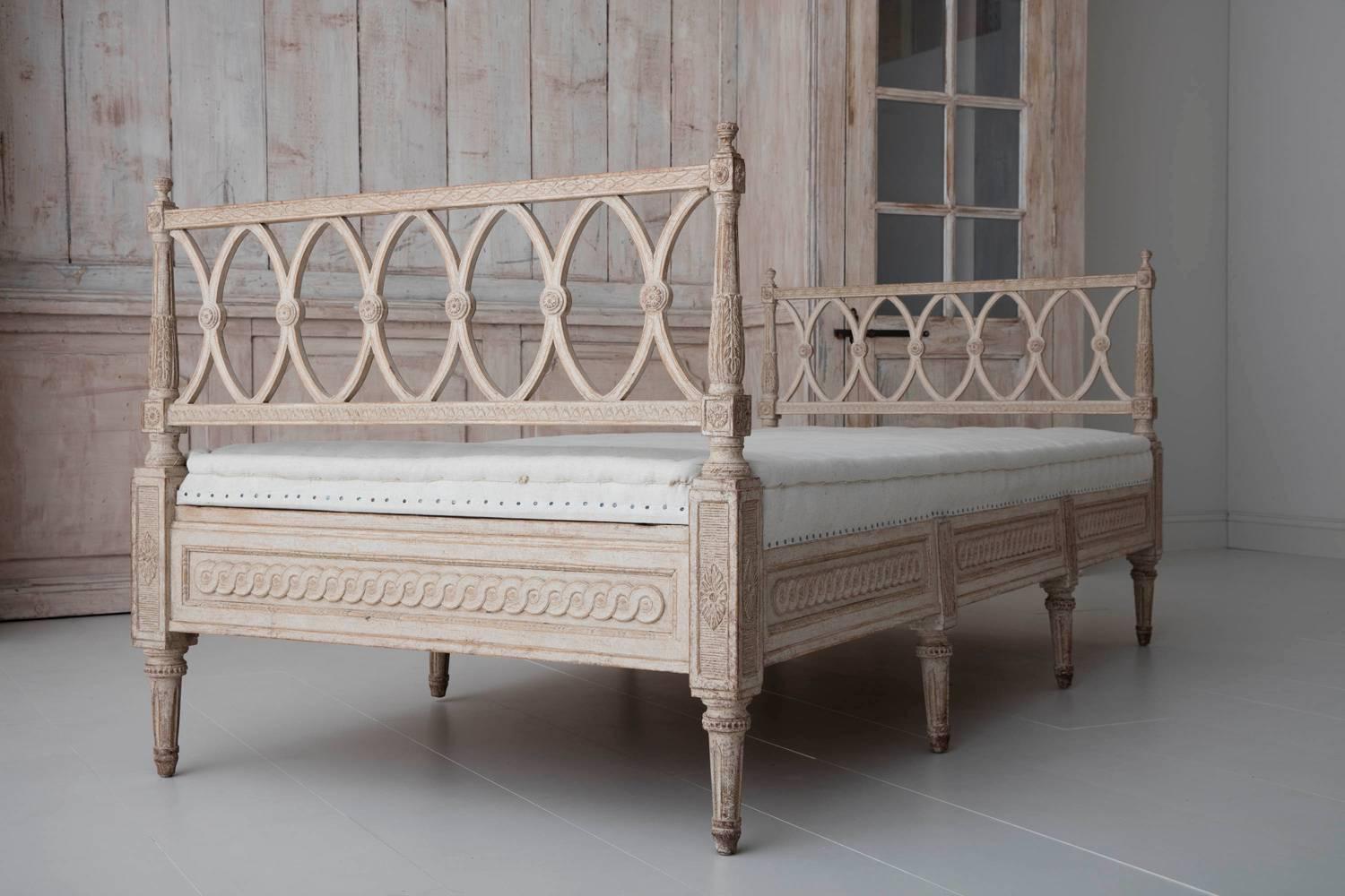 This is a beautifully carved Swedish Gustavian Style freestanding daybed, newly upholstered in hand-stiched linen. The sides are decorated with acanthus leaves and rosettes. The frame is finished on all four sides and features Guilloché carvings
