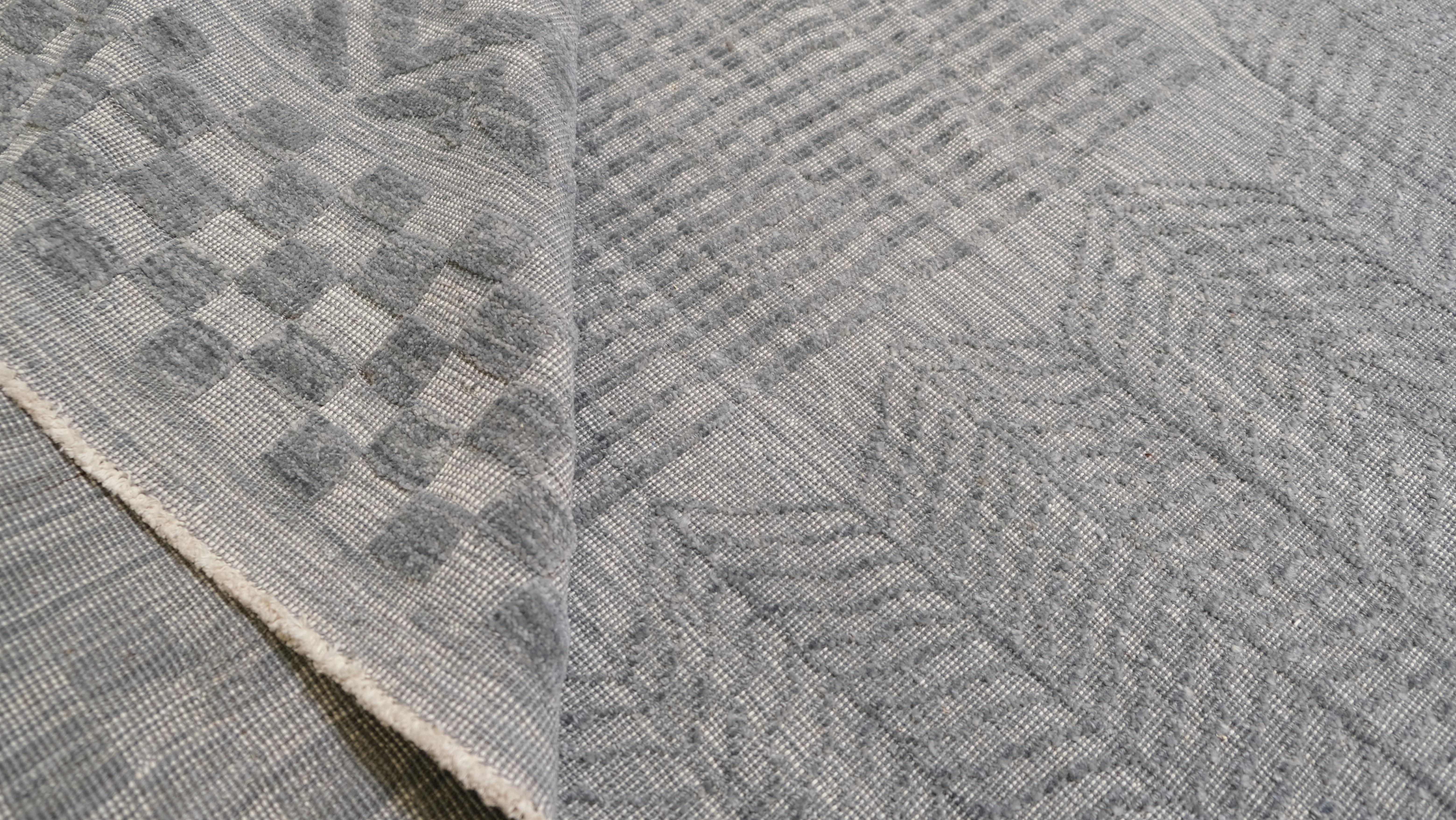 Élevez votre intérieur grâce à l'élégance discrète de ce tapis en laine noué à la main. Avec sa palette harmonieuse de bleu gris et ses motifs géométriques et abstraits complexes, ce tapis allie sans effort un design moderne à un savoir-faire