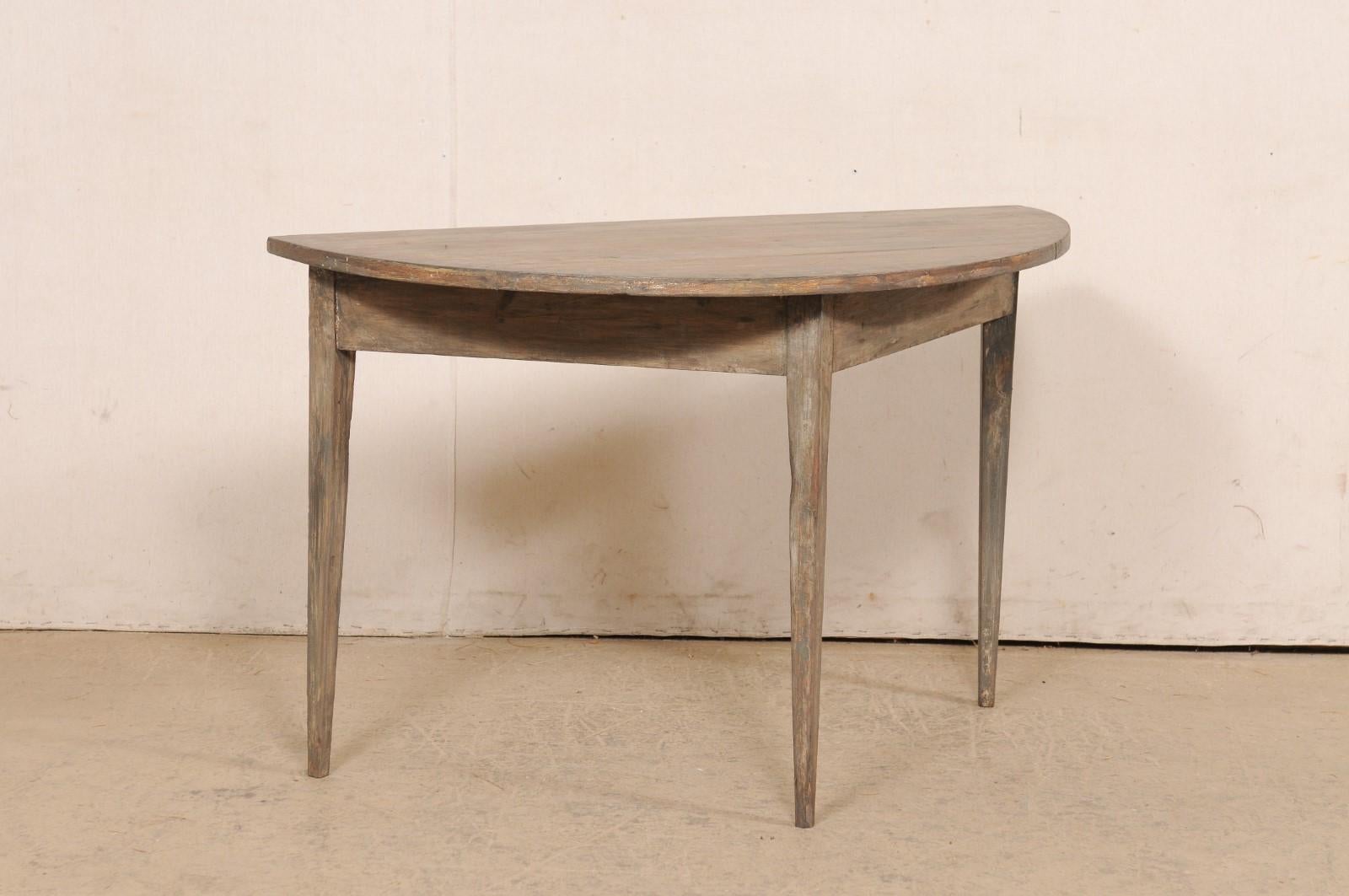 A Swedish single wooden demi-lune table from the turn of the 19th and 20th century. This antique table from Sweden features a semi-circular, or half moon top, over a triangular shaped apron. The skirt is clean and plain, and the piece is raised upon