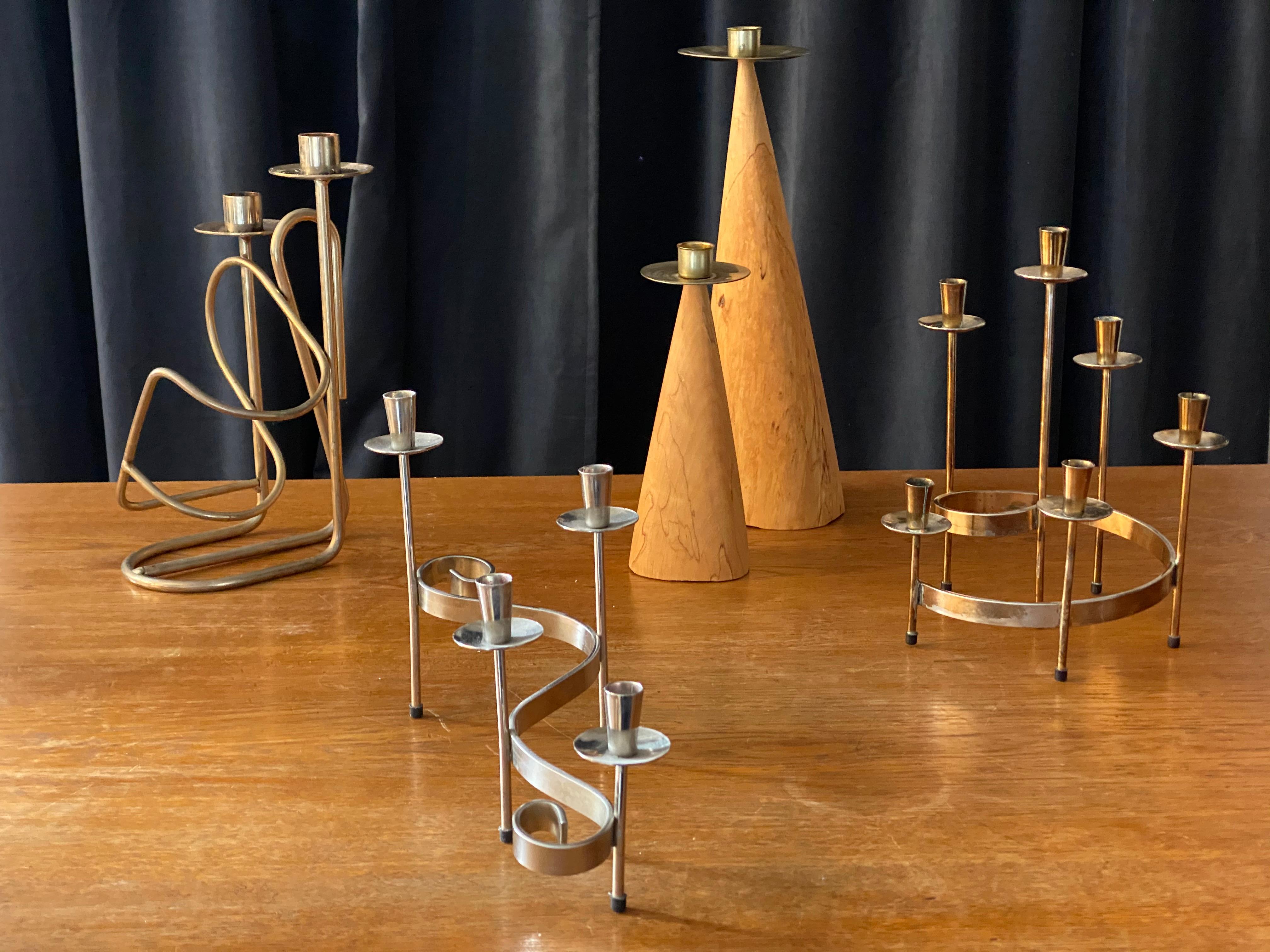 An assorted collection of 2 candlesticks and 3 candelabra, Swedish, circa 1950s-1970s. Candlesticks of studio production, circa 1970s, 2 candelabra by Gunnar Ander for Ystad Metall, circa 1950s. One candelabra also functioning as a bottle holder,
