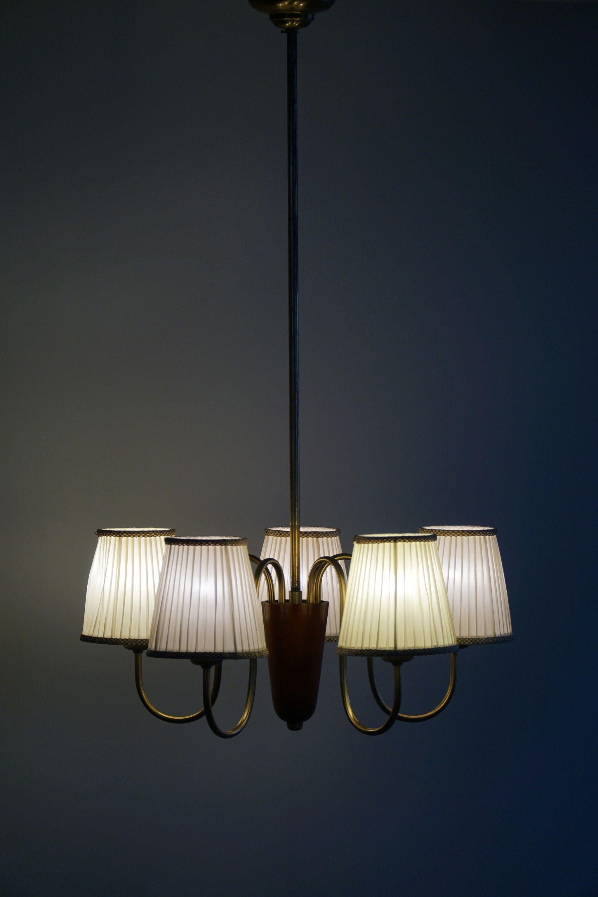 This classic chandelier exudes timeless elegance with its Mid-Century Modern design, crafted in the 1950s by a Swedish designer. The fixture features a charming combination of brass and teak, creating a harmonious blend of warmth and sophistication.