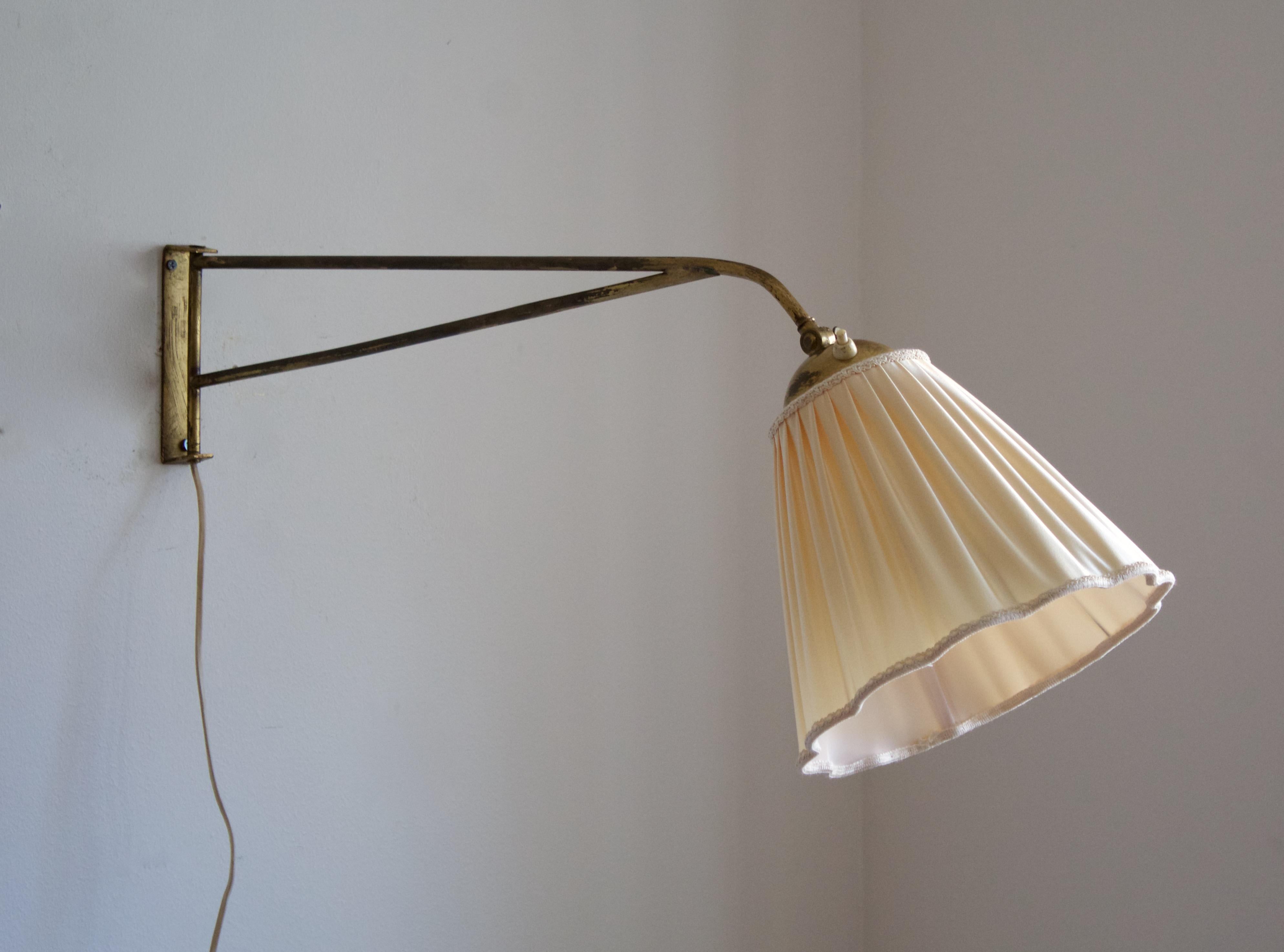 A functionalist wall light / task light, designed and produced in Sweden, 1940s. Features brass. Original fabric lampshade.

Stated dimensions with lampshade attached as is illustrated in the primary image.