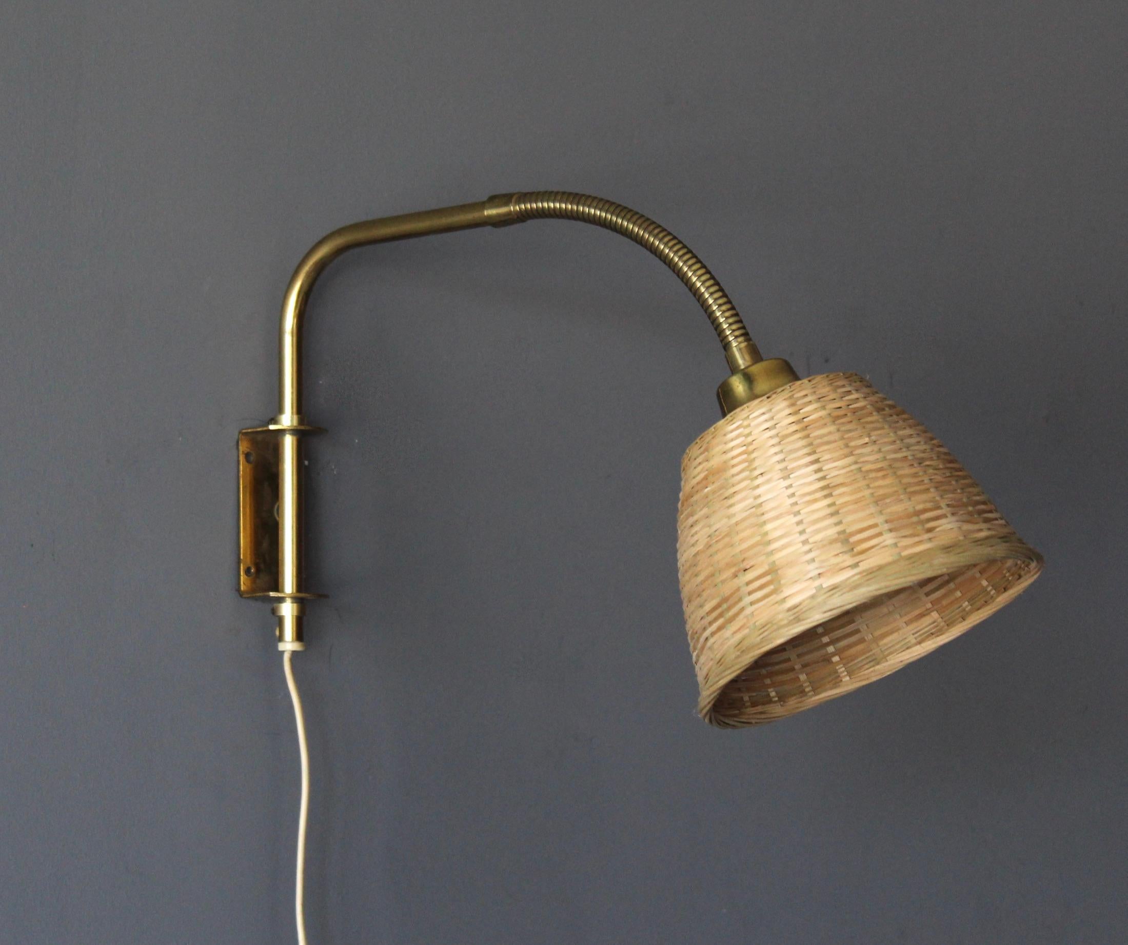 A functionalist wall light / task light, designed and produced in Sweden, 1940s-1950s. Features brass. Assorted vintage rattan lampshade.

Takes one lightbulb on E27 socket. No stated max wattage, not UL listed.

