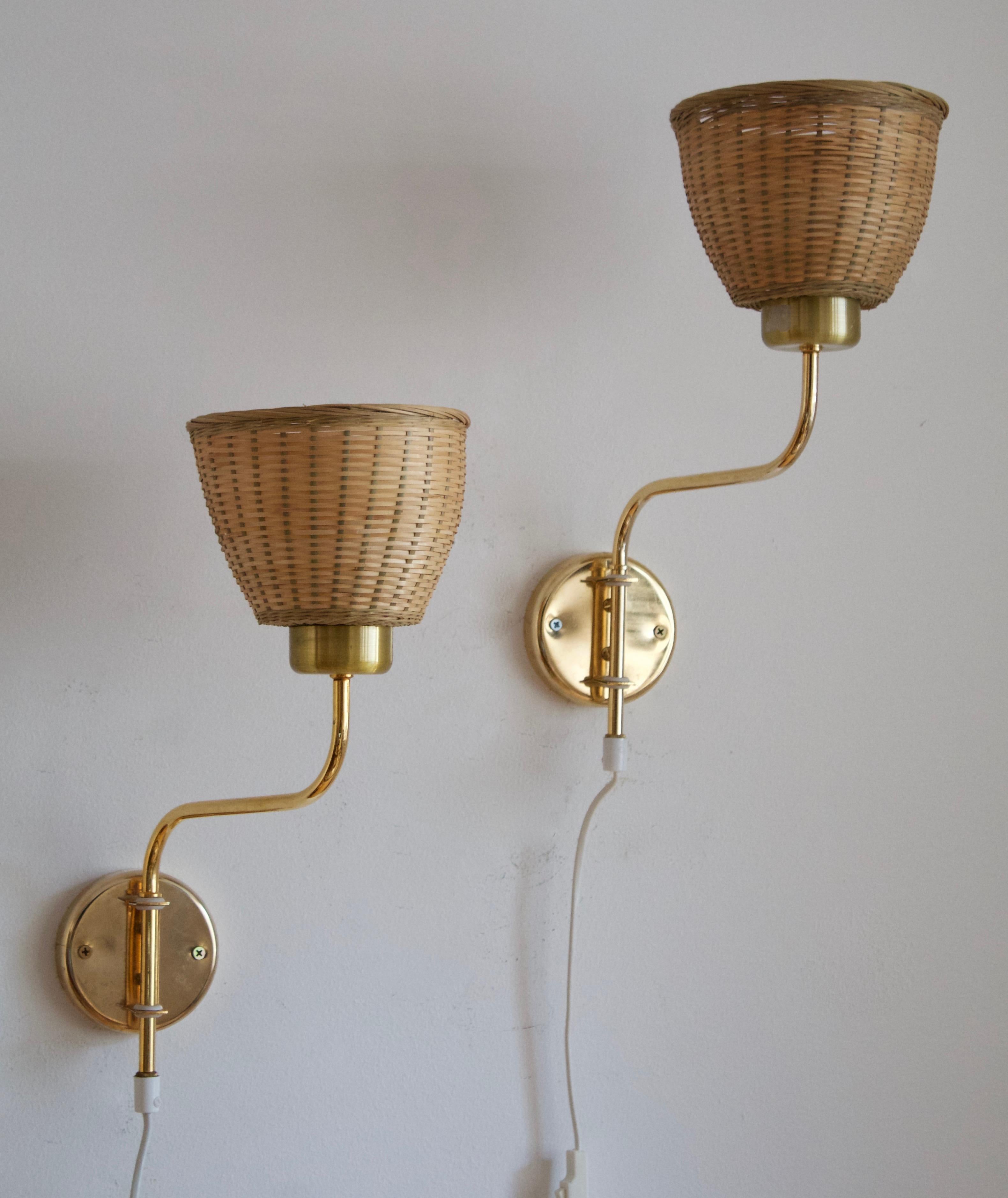 A pair of wall lights, designed and produced in Sweden, c. 1970s. Features brass, assorted vintage rattan lampshades.

Stated dimensions with lampshade attached.
