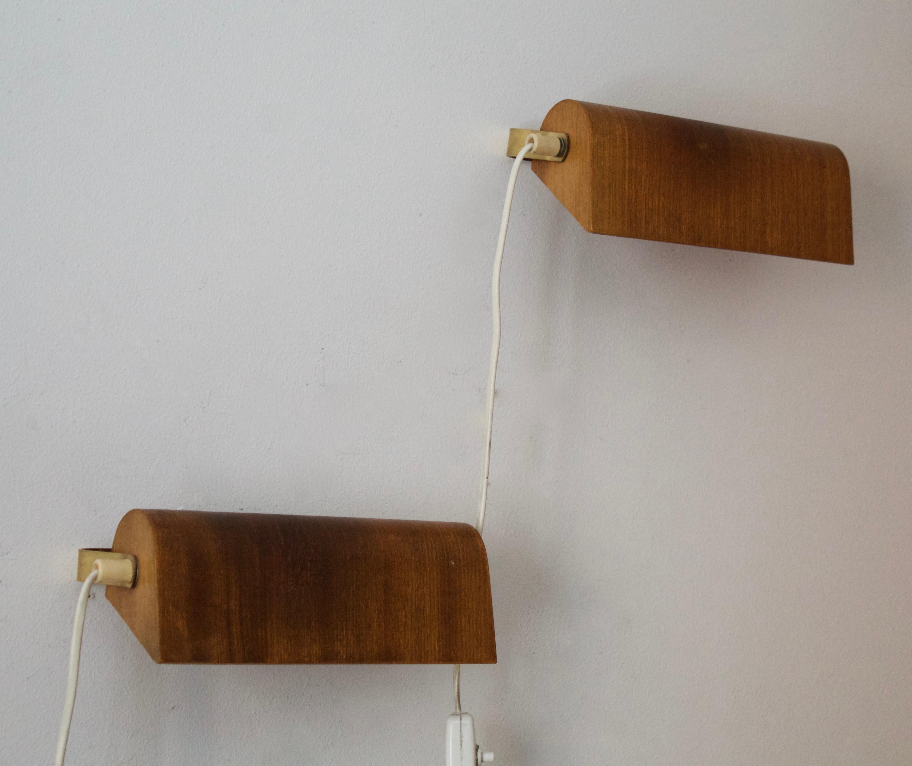 A pair of small adjustable wall lights. Designed and produced in Sweden, 1950s. Features brass and teak.
