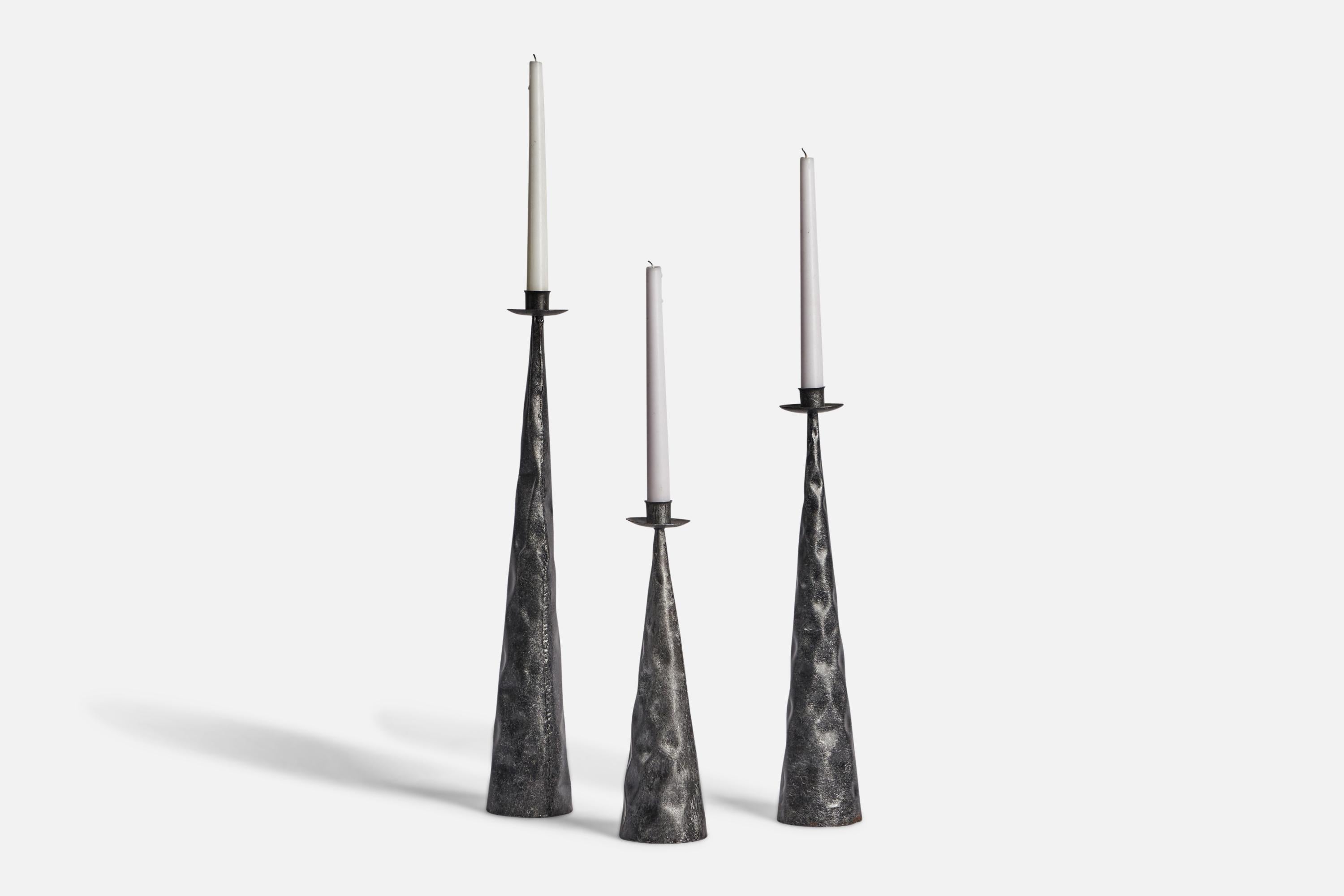 A set of three hammered iron candlesticks designed and produced in Sweden, c. 1970s.

Holds 0.8” diameter candles. Set of 3. 
Tallest candle holder: 19.25” height
Medium candle holder: 16” height
Short candle holder: 12” height 
All have base