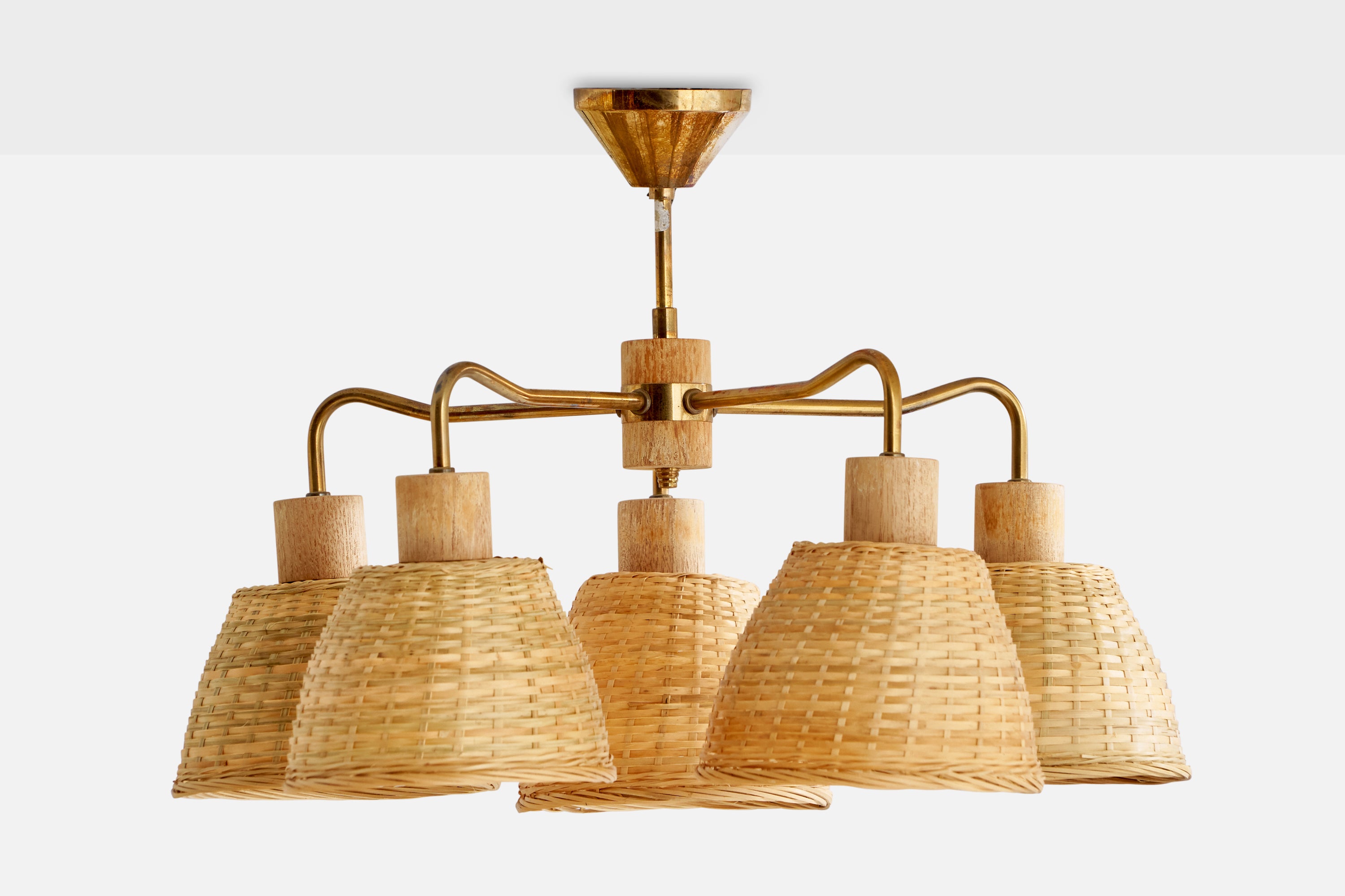 A brass, oak and rattan chandelier designed and produced in Sweden, 1950s.

Dimensions of canopy (inches): 2.38” H x 2.8” Diameter
Socket takes standard E-26 bulbs. 5 sockets.There is no maximum wattage stated on the fixture. All lighting will be