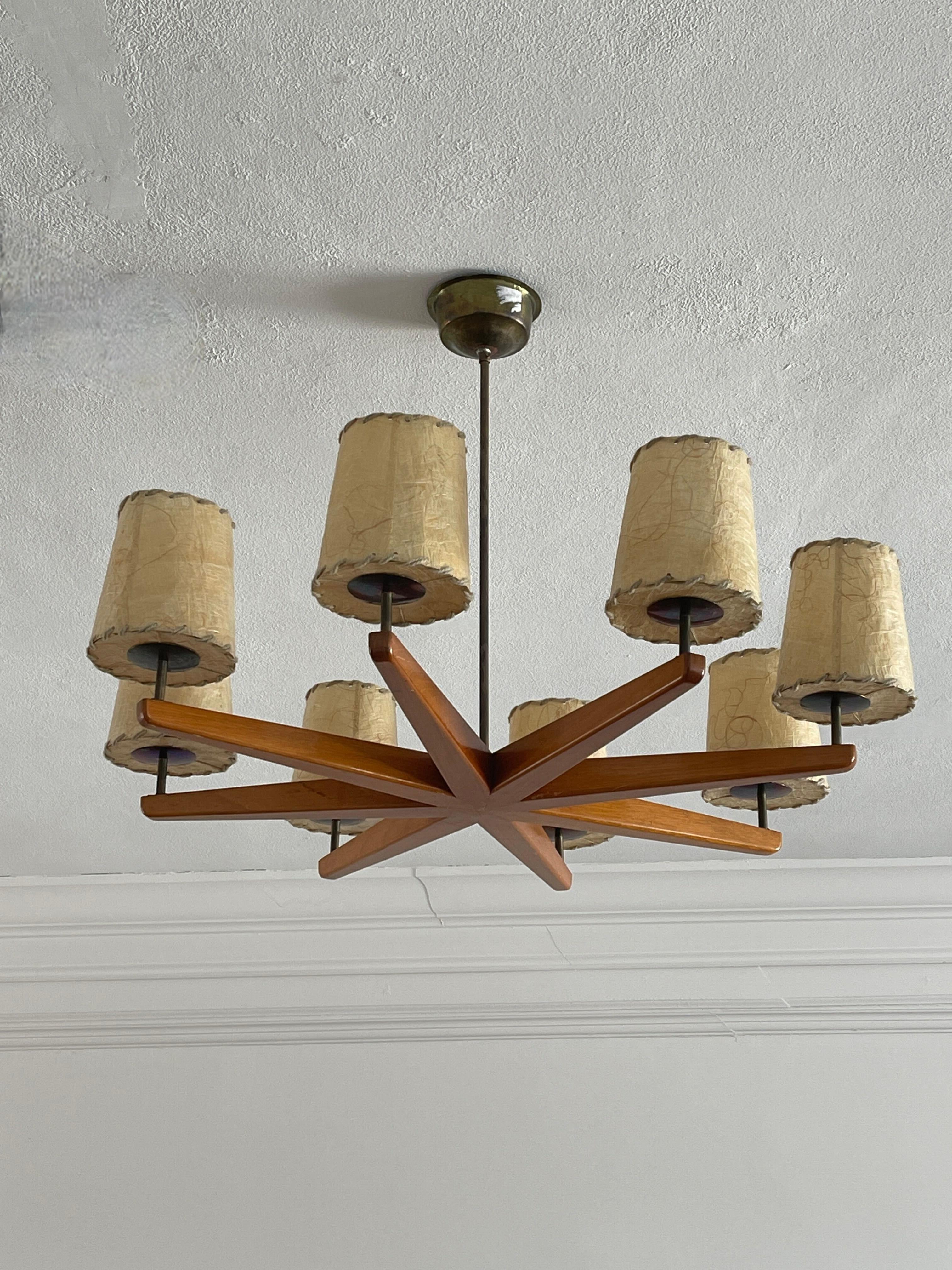 An eight-armed chandelier in wood, brass, and parchment paper. Designed and produced in Sweden, 1930s.