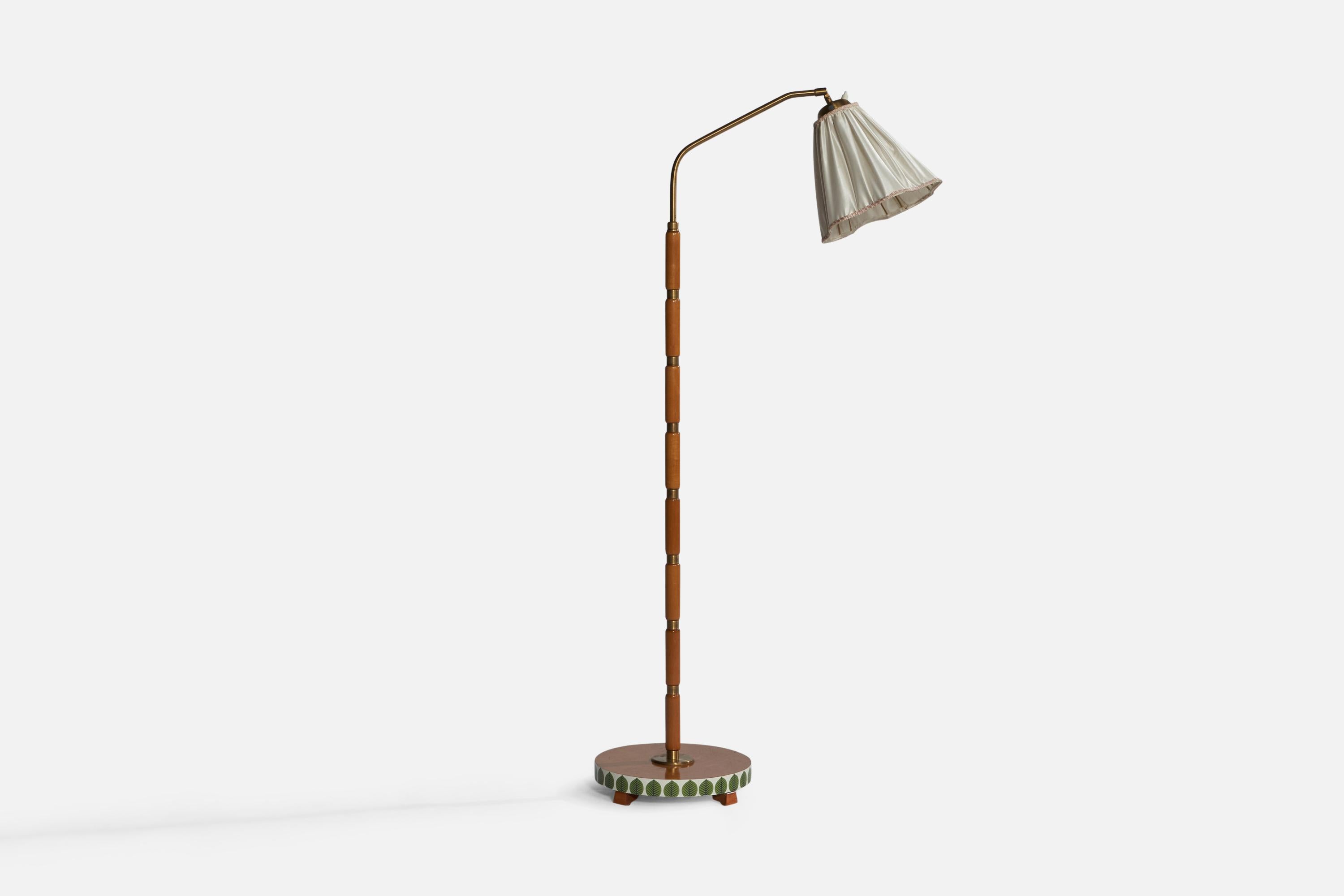 An adjustable brass, teak and off-white fabric floor lamp designed and produced in Sweden, 1940s.

With a later added laminated print to base illustrating a Stig Lindberg pattern.

Overall Dimensions (inches): 55.1” H x 12.5” W x 29” D. Stated