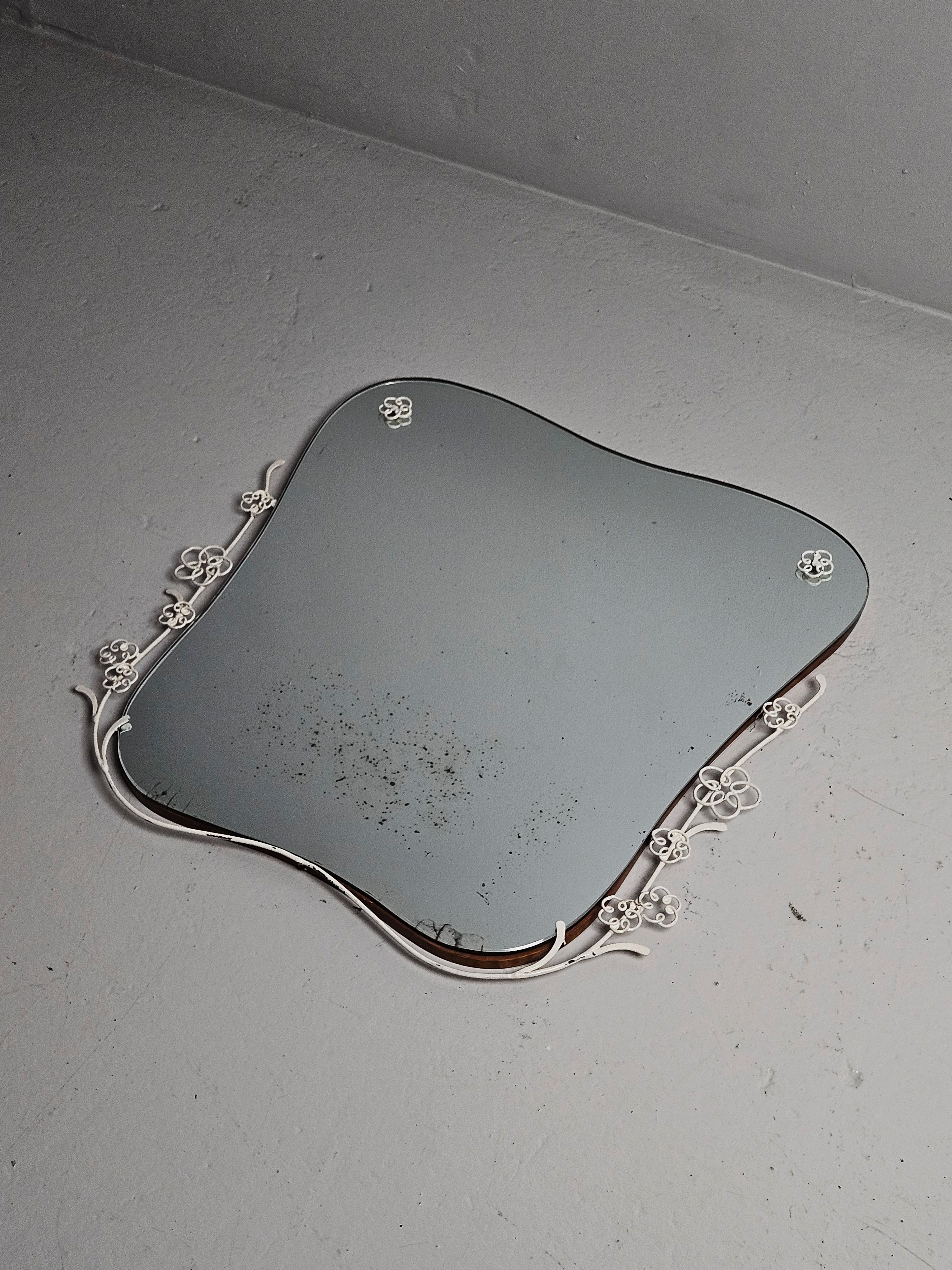 Specchio da parete unico nel suo genere, realizzato da un designer sconosciuto in Svezia negli anni Trenta. 

Realizzato in forma organica con decori floreali in ferro laccato bianco. 

Vetro a specchio con macchie e crepe.