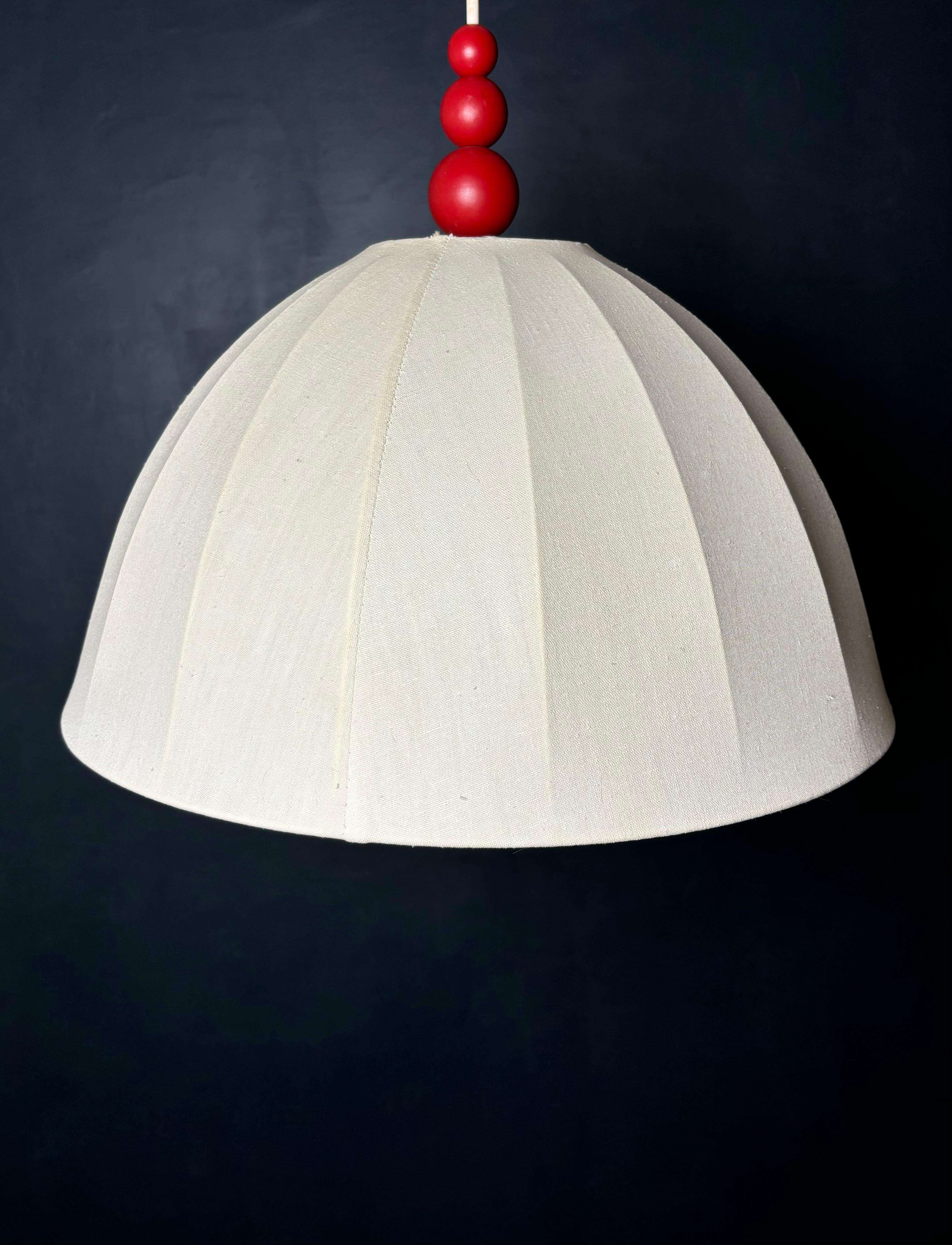 Pendente vintage scandinavo della metà del secolo scorso con paralume in tessuto bianco crema a forma di cupola su supporto in metallo e tre globi di legno rosso sulla parte superiore. Nello stile organico e moderno di Josef Frank, Svenskt Tenn,