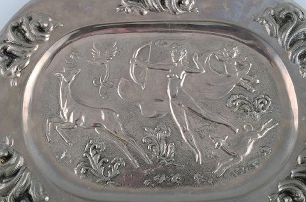 Swedish designer. Large oval serving dish in metal with a classicist hunting scene.
Diana the goddess of the hunt,
1910-1920.
Measures: 39 x 29.5 cm.
In excellent condition.