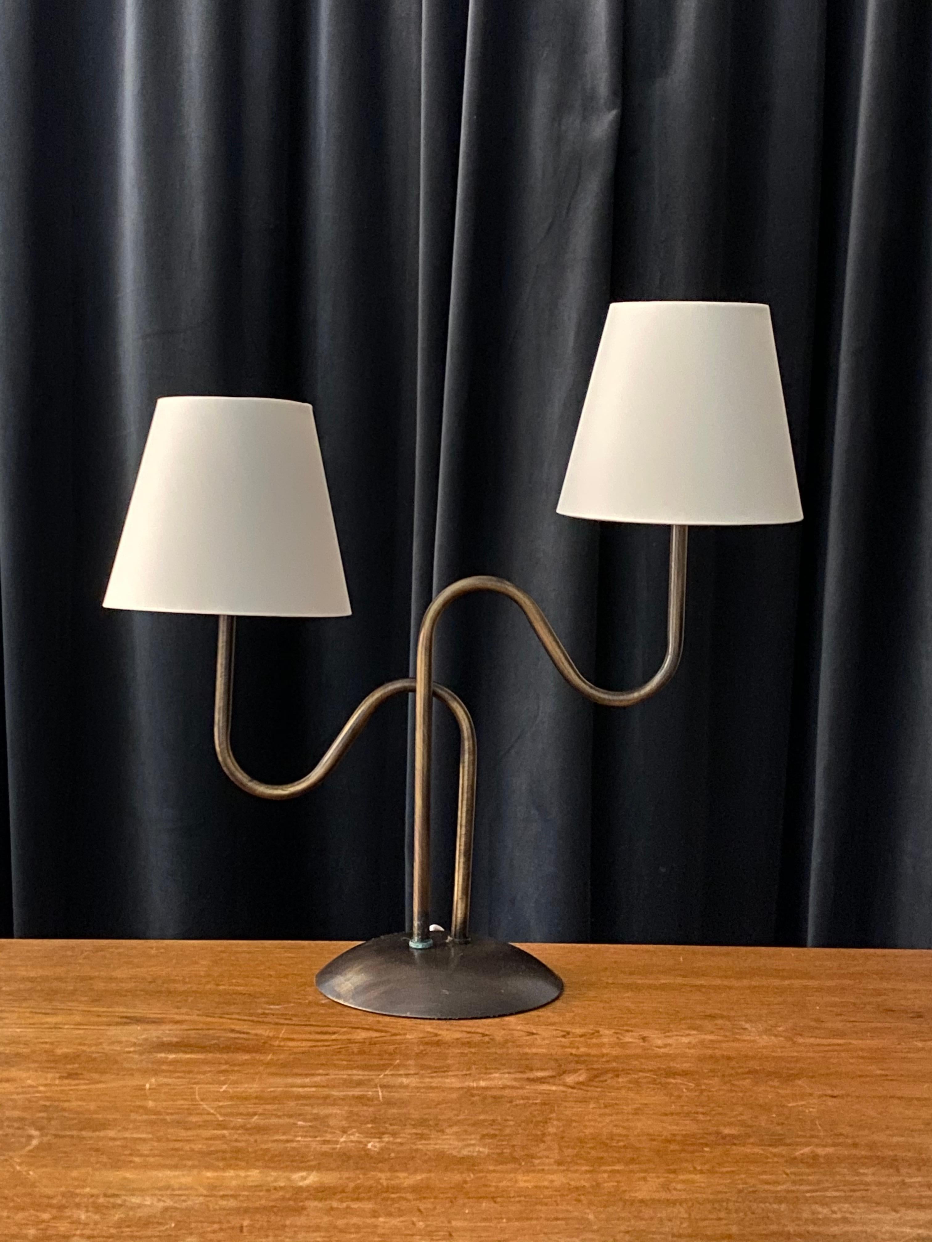 A two armed organic table lamp. By an unknown Swedish designer and maker. In brass. 

Lampshades, on bulb-clips, are attached for illustration. Work is sold excluding lampshades. Dimensions stated excluding lampshades and lightbulbs.

Other