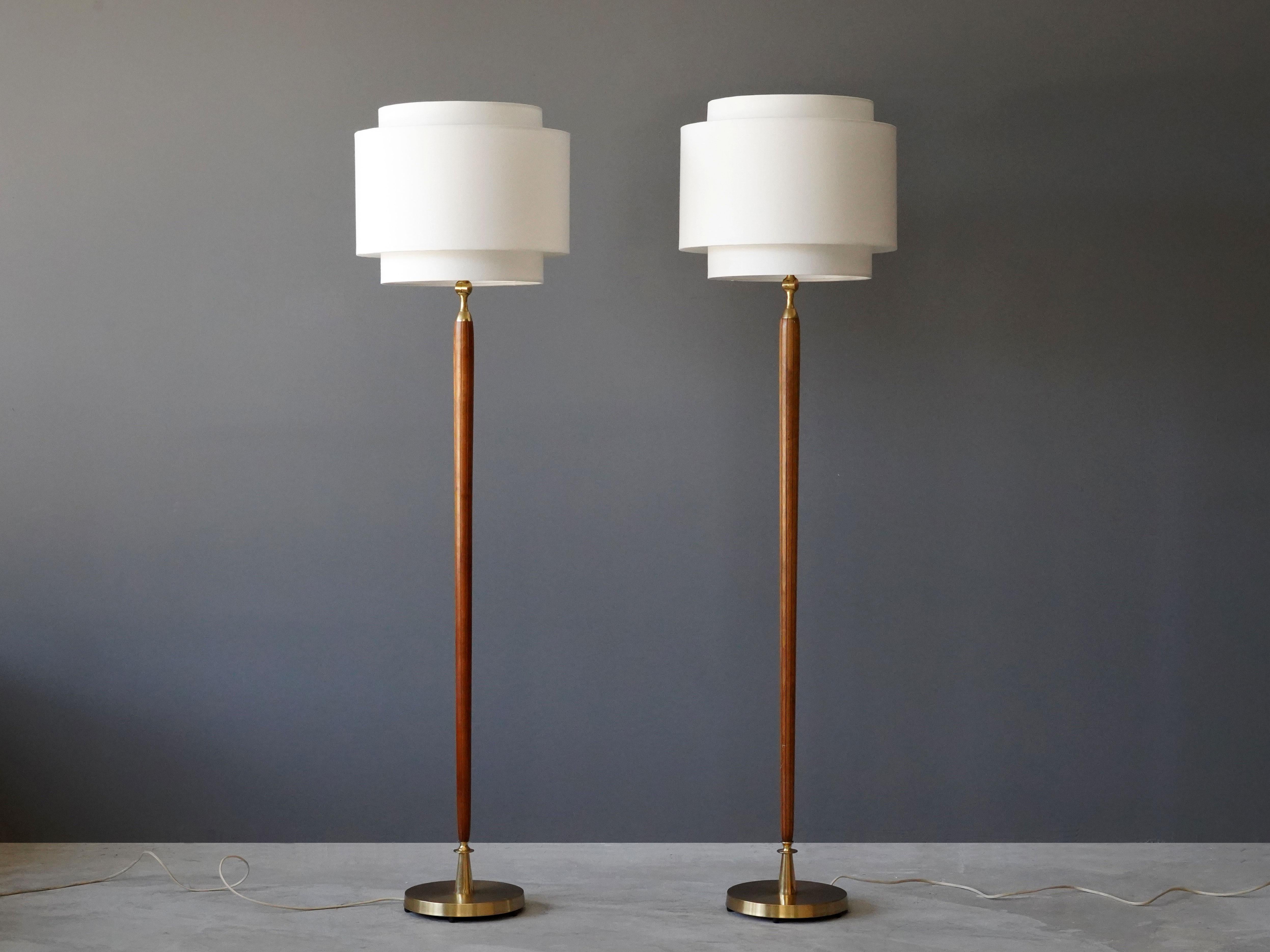 A pair of floor lamps. Designed by an unknown Swedish designer. Produced in the 1940s. Features finely carved wooden rods on brass bases. Screens are adjustable and can be tilted. 

Other designers working in similar style include Paavo Tynell,