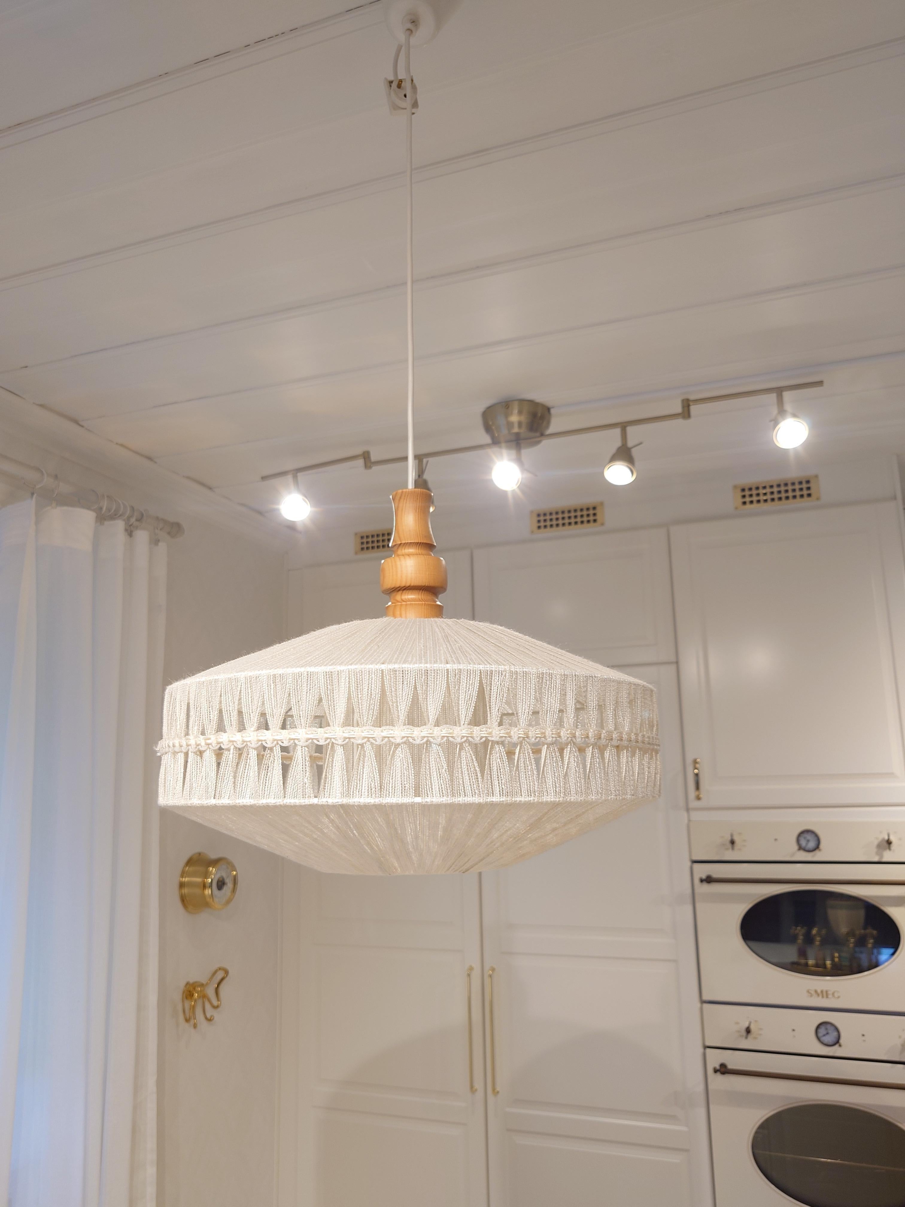 
Una lampada a sospensione in tessuto bianco crema progettata e prodotta in Svezia, negli anni '60 circa.

Eleva qualsiasi spazio con questa lampada a sospensione unica, un mix perfetto di texture naturali e design vintage. La lampada è dotata di un
