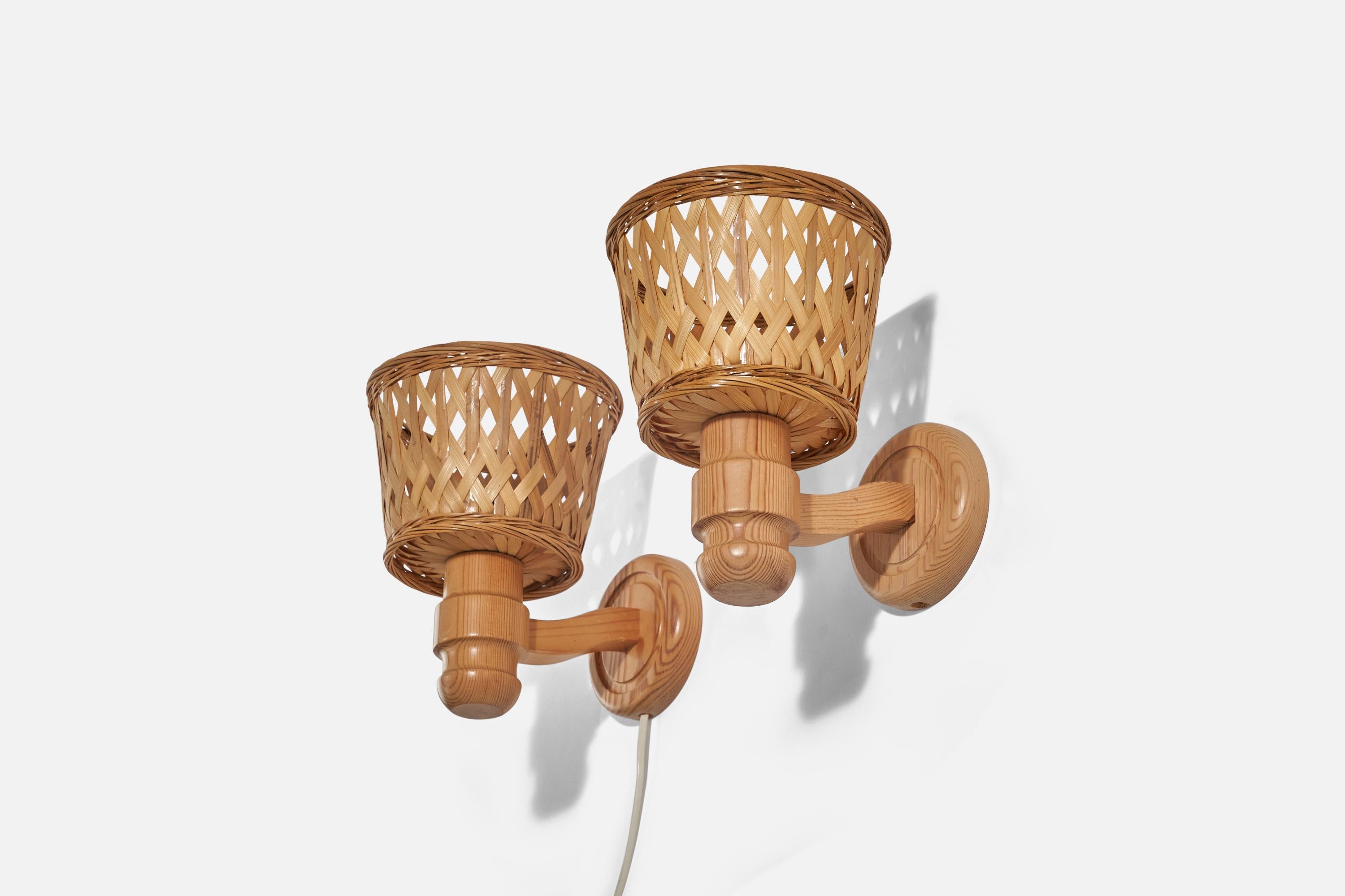 A pair of pine and rattan sconces/ wall lights designed and produced in Sweden, 1970s.

Sold with Lampshades. Dimensions stated are of sconces with lampshades. 

Dimensions of back plate (inches) : 4.56 x 4.56 x 0.81 (height x width x