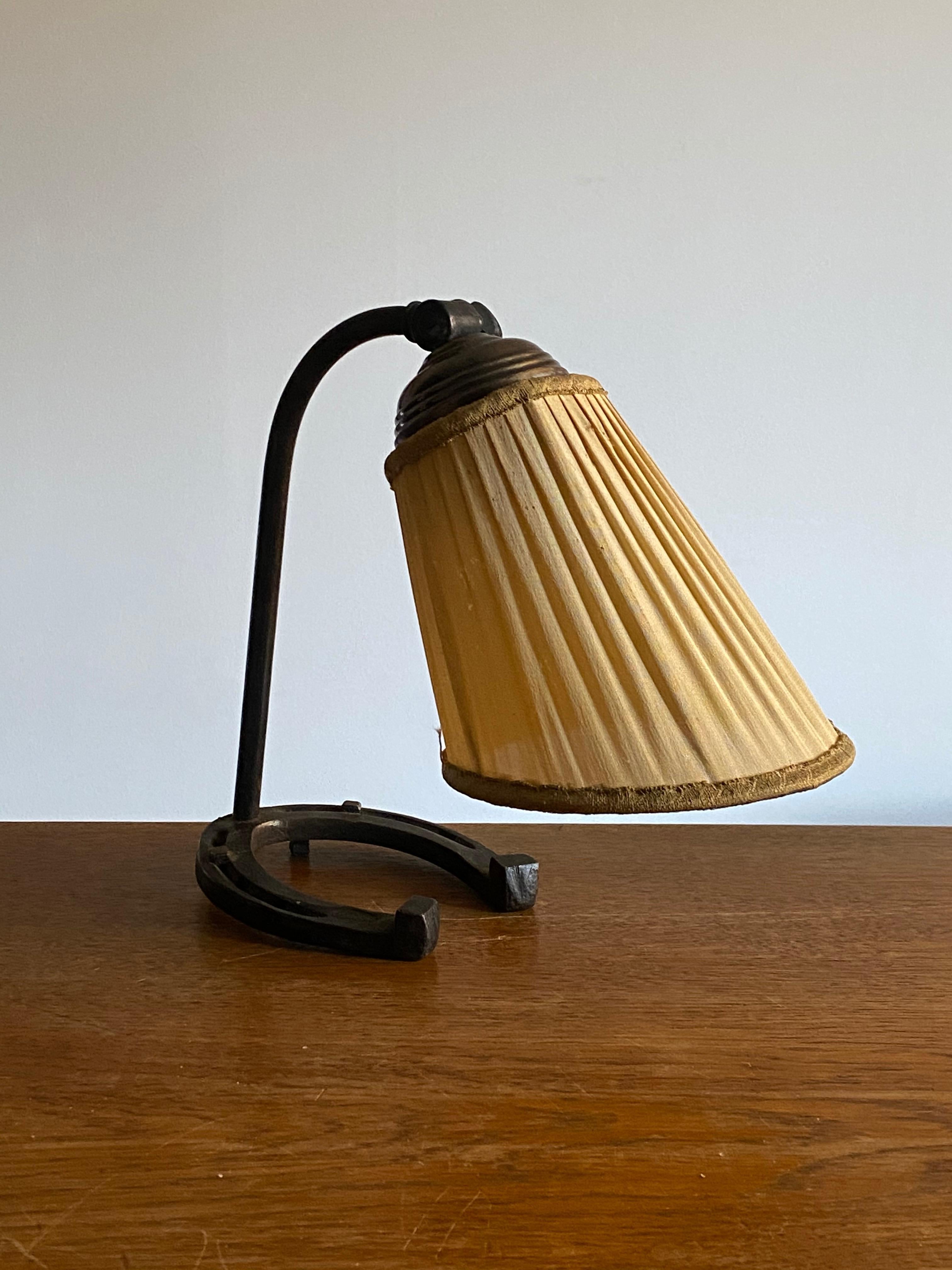 A small table lamp or desk light. Base in cast iron with horse-shoe form. The original lampshade needs replacement or recovering.

  
