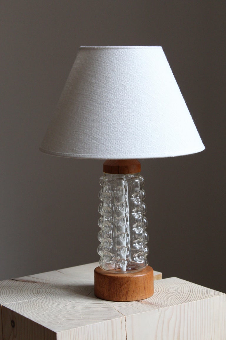 A table lamp, in teak and glass.

Shade not included.

Other designers of the period include Paavo Tynell, Josef Frank, Lisa Johansson-Pape, and Alvar Aalto.