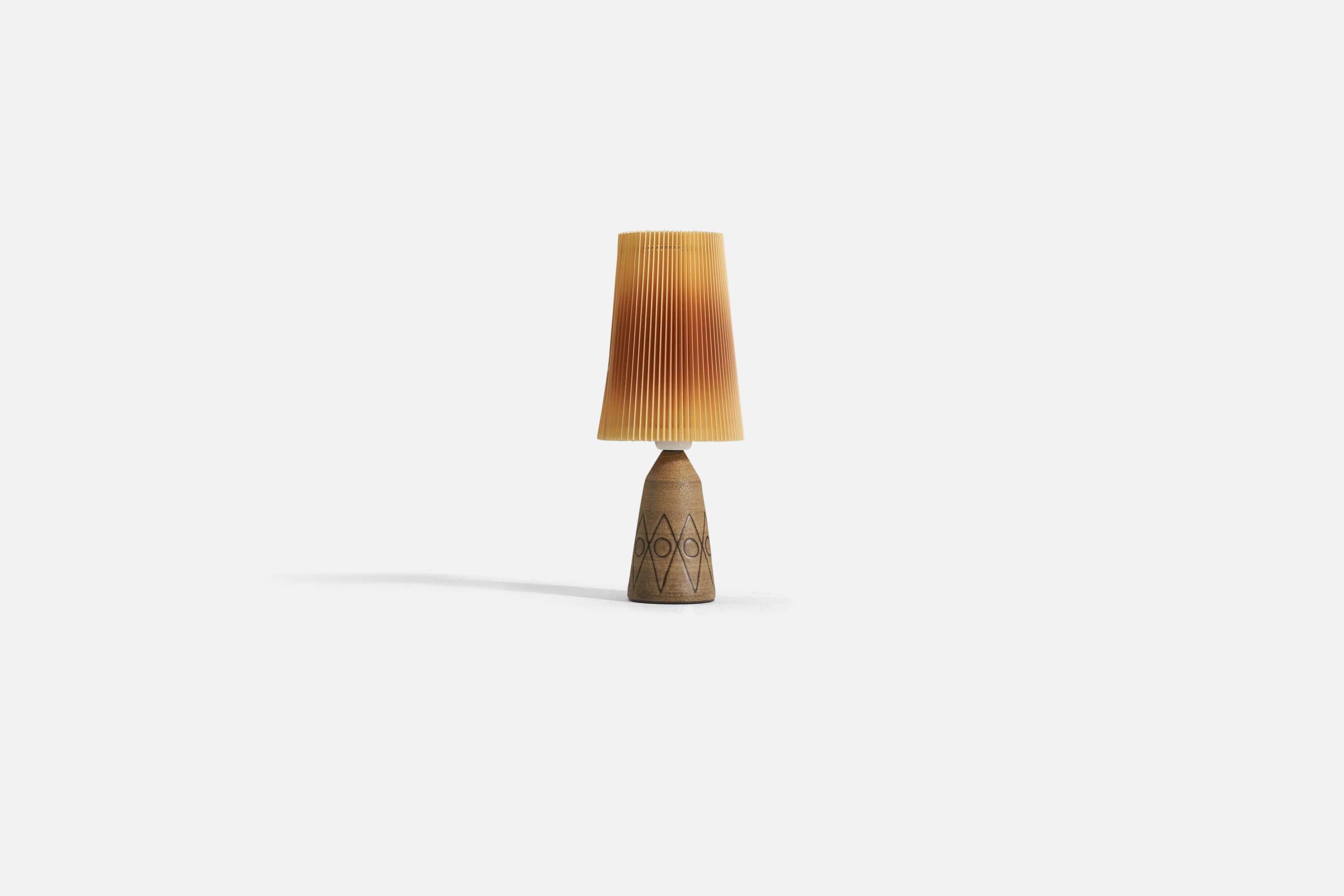 Lampe de table en céramique brune incisée, conçue et produite en Suède, vers les années 1960. 

Vendu avec un abat-jour illustré. Les mesures indiquées comprennent l'abat-jour.