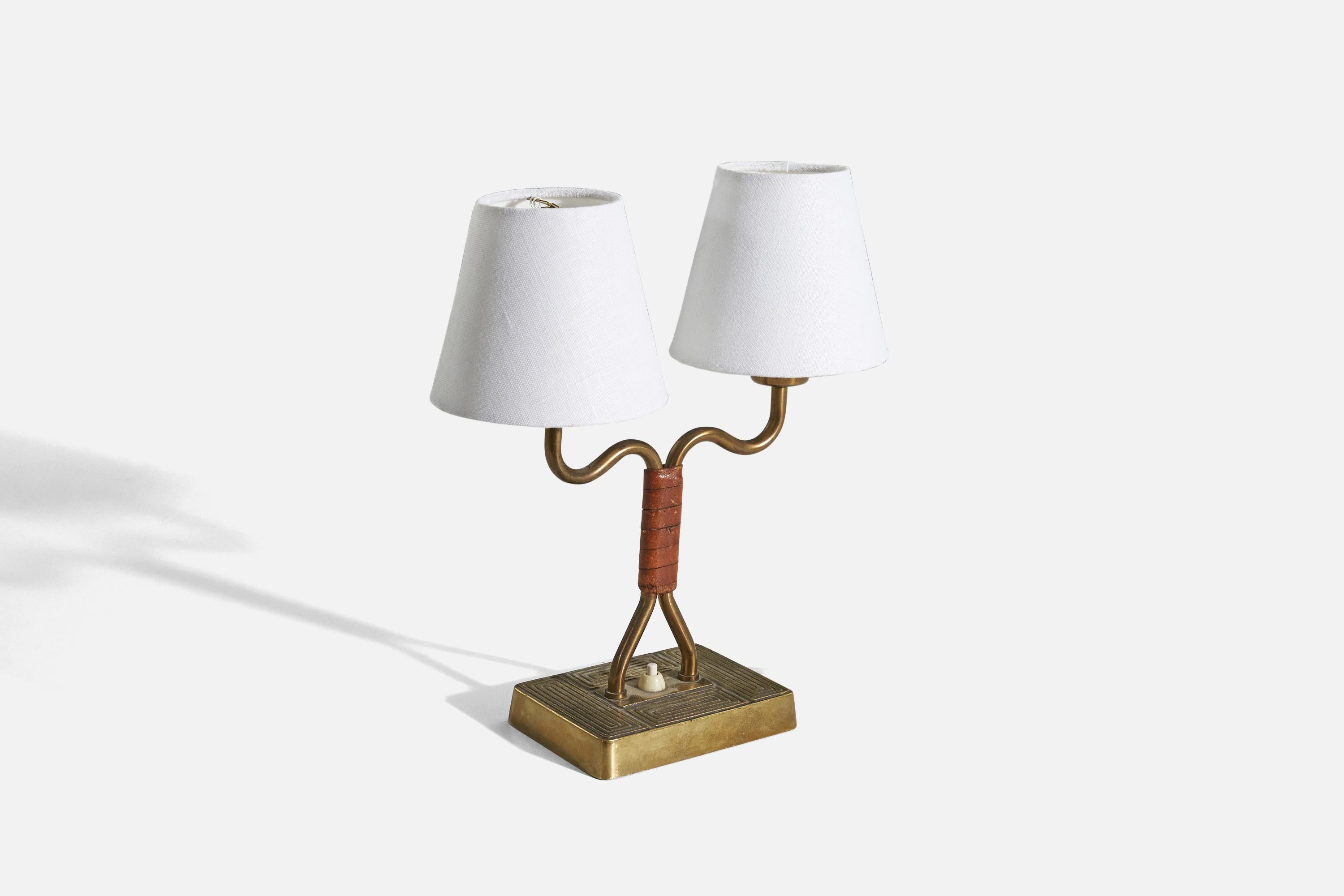 A brass and leather table lamp designed and produced in Sweden, c. 1940s.

Sold without lampshades. 
Dimensions of Lamp (inches) : 10.62 x 8.5 x 4.25 (H x W x D)
Dimensions of Shade (inches) : 3 x 5 x 4.5 (T x B x S)
Dimension of Lamp with