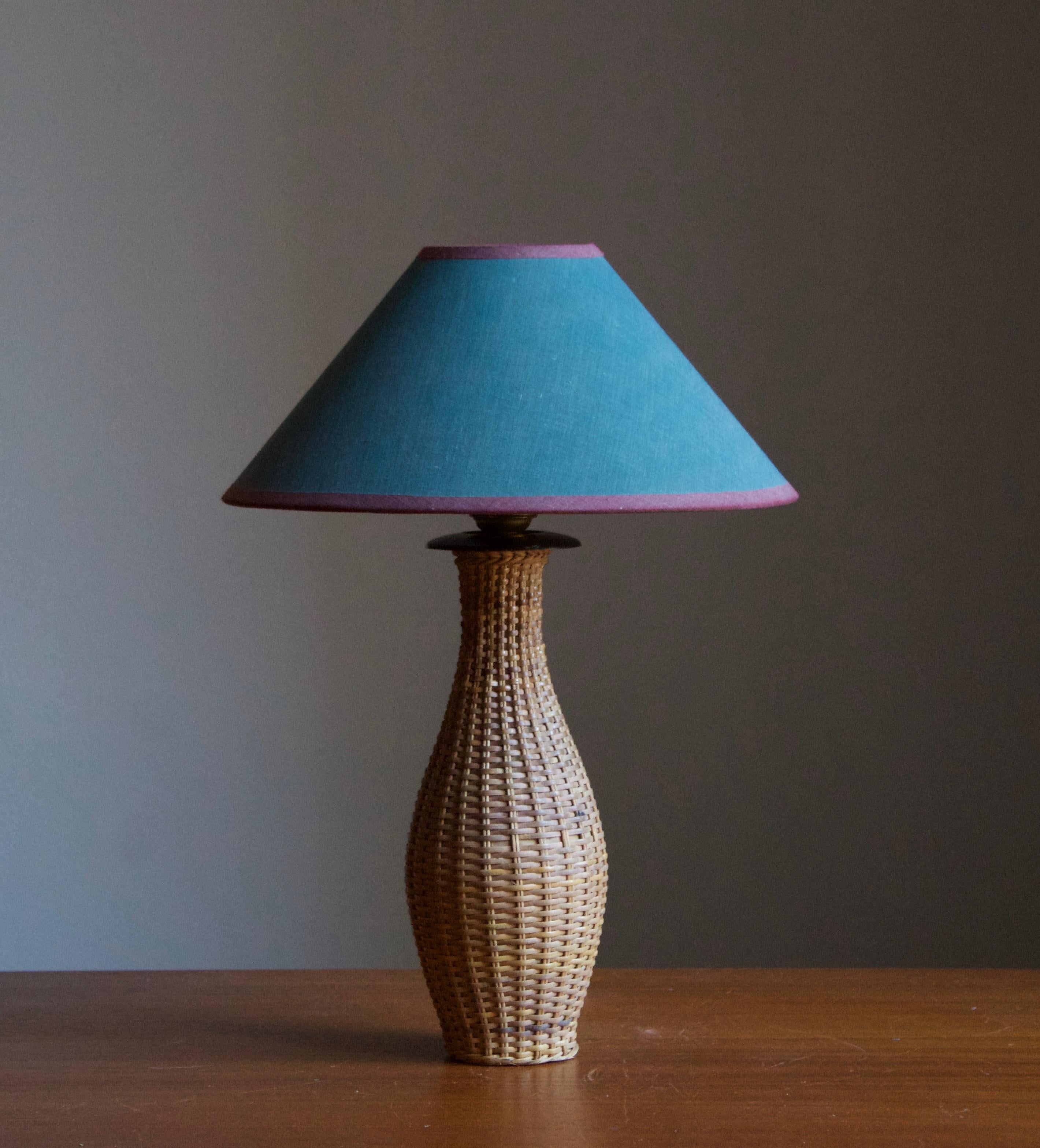 A table lamp, designed and produced in Sweden c. 1950s-1960s. Features finely braided rattan over a turned wooden base. 

Stated dimensions exclude lampshade. Height includes socket. Vintage lampshade possibly original to the lamp.

Takes one