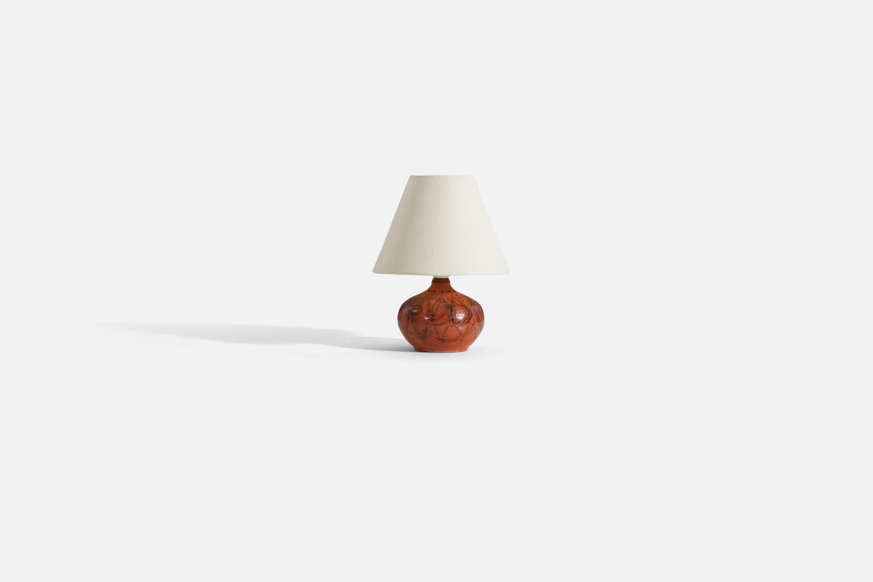 A red-orange glazed stoneware table lamp, designed and produced in Sweden, 1960s.

Measurements listed are of the lamp itself. Sold without lampshade.
For reference:
Measurements of shade (inches): 3.75 x 8.25 x 6.25 (T x B x S)
Measurements