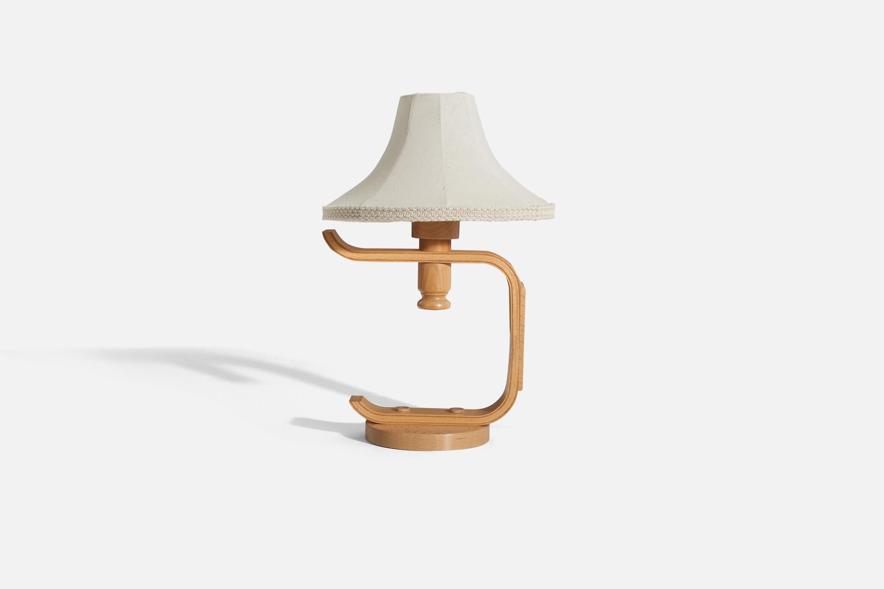 A wooden table lamp with a fabric lampshade, designed and produced by a Swedish designer, Sweden, 1970s.

Sold with lampshade. 
Dimensions of Lamp (inches) : 12.8125 x 6.125 x 9.75 (H x W x D)
Dimensions of Shade (inches) : 3.5 x 11 x 7.25 (T x B x